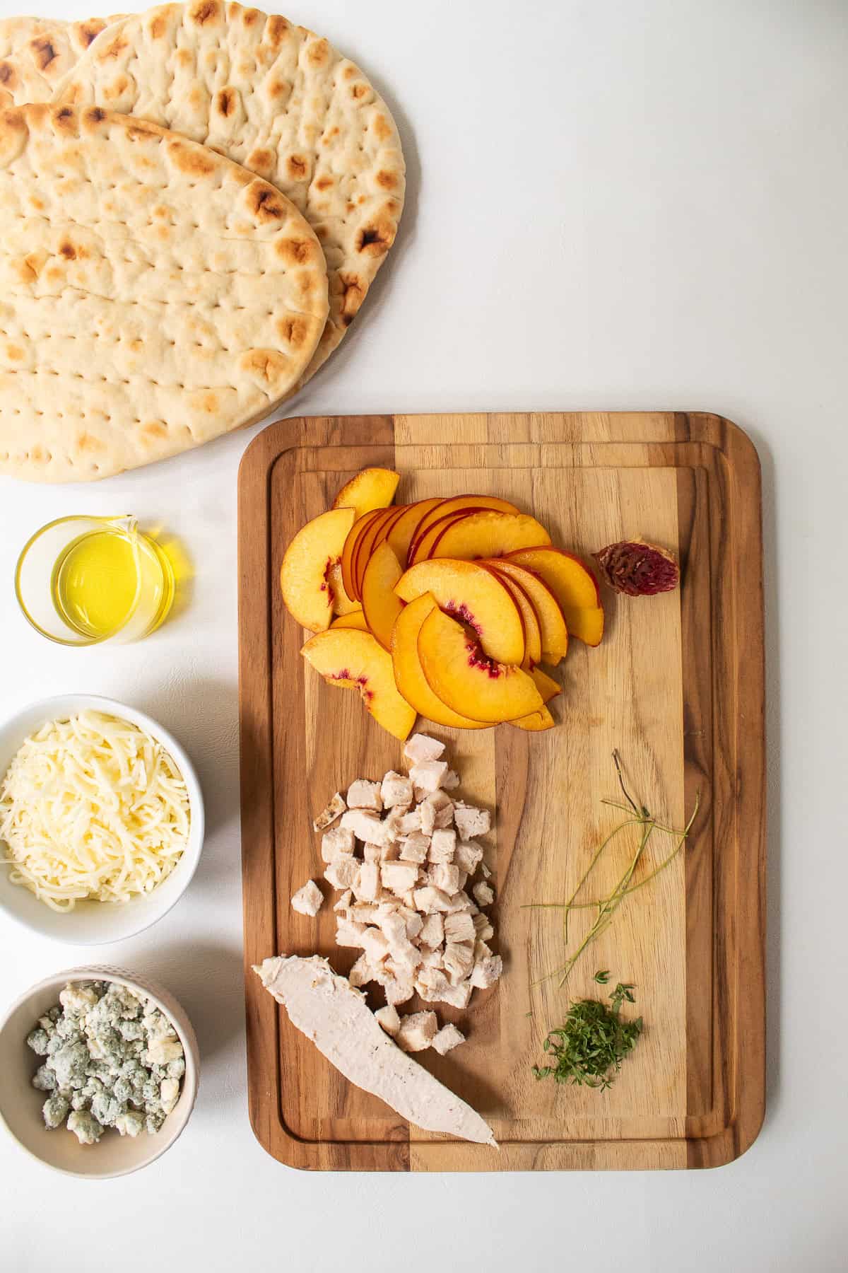 Toppings for the nectarine pizza are prepared on a wooden cutting board.