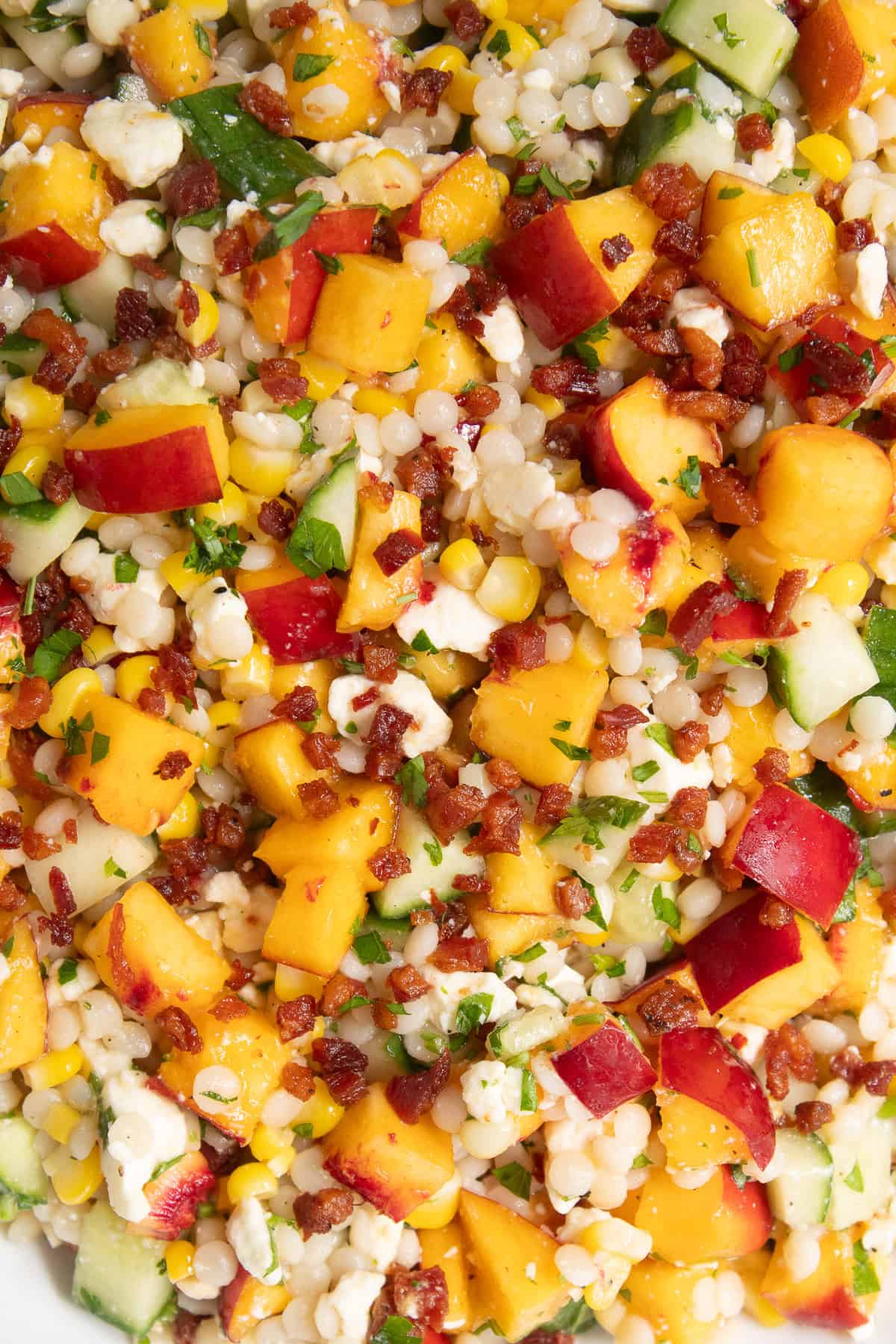 This detail image shows the pieces of nectarine, cucumber, and feta speckled with parsley and pancetta.