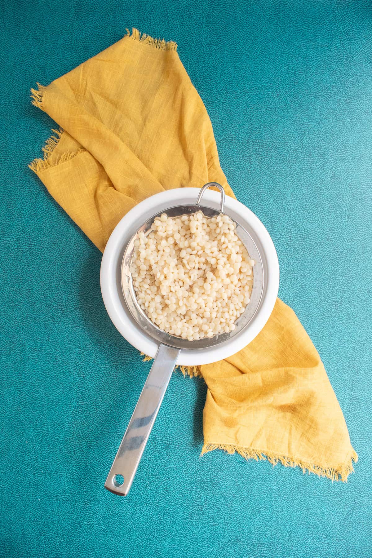 The couscous is drained using a mesh strainer.