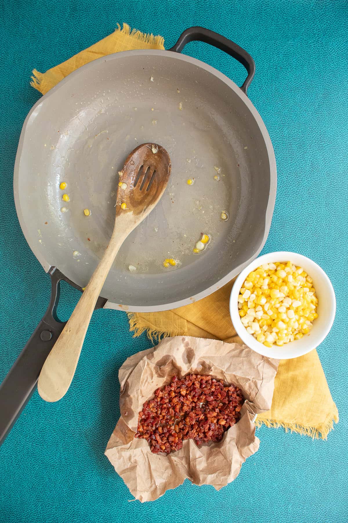 The cooked corn is removed from the pan using a slotted spoon.