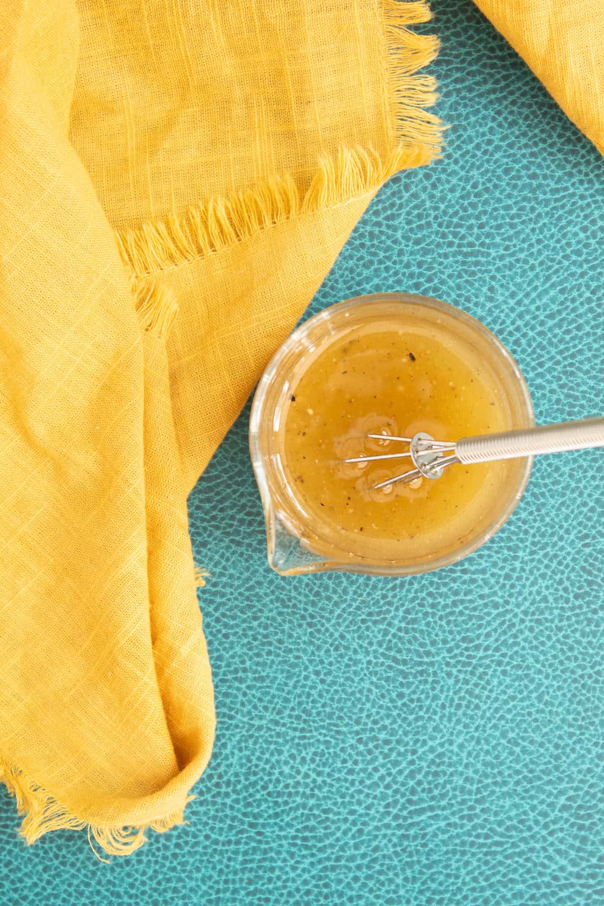 The salad dressing is whisked until combined, resulting in a pale golden yellow mixture.