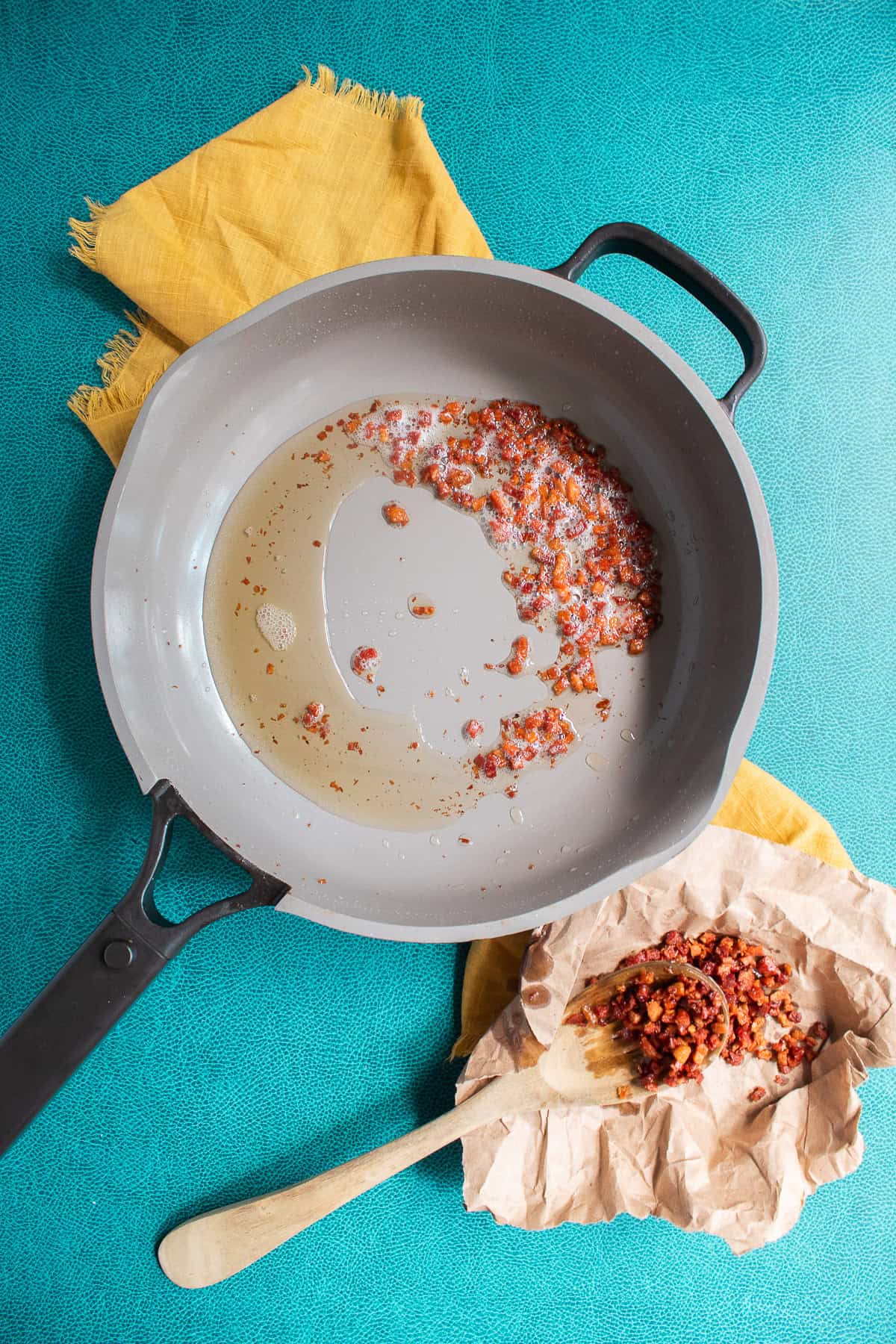 The crispy pancetta is removed from the pan using a slotted spoon.