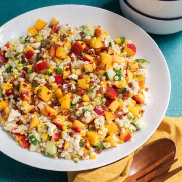 The finished salad has visible pieces of nectarine, cucumber, pancetta, corn, and parsley.