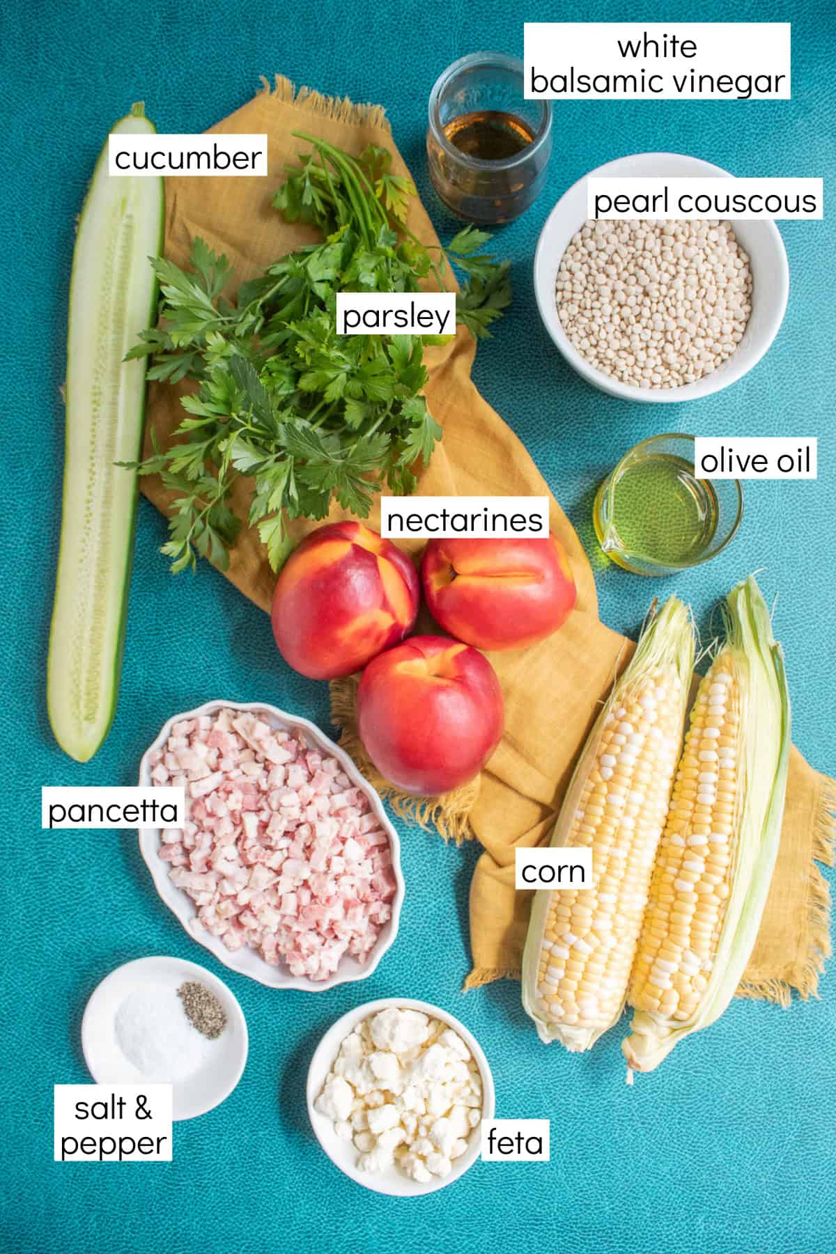 Ingredients for the recipe are displayed and labeled with white text boxes including the words cucumber, white balsamic vinegar, pearl couscous, parsley, nectarines, olive oil, pancetta, corn, salt & pepper, and feta.