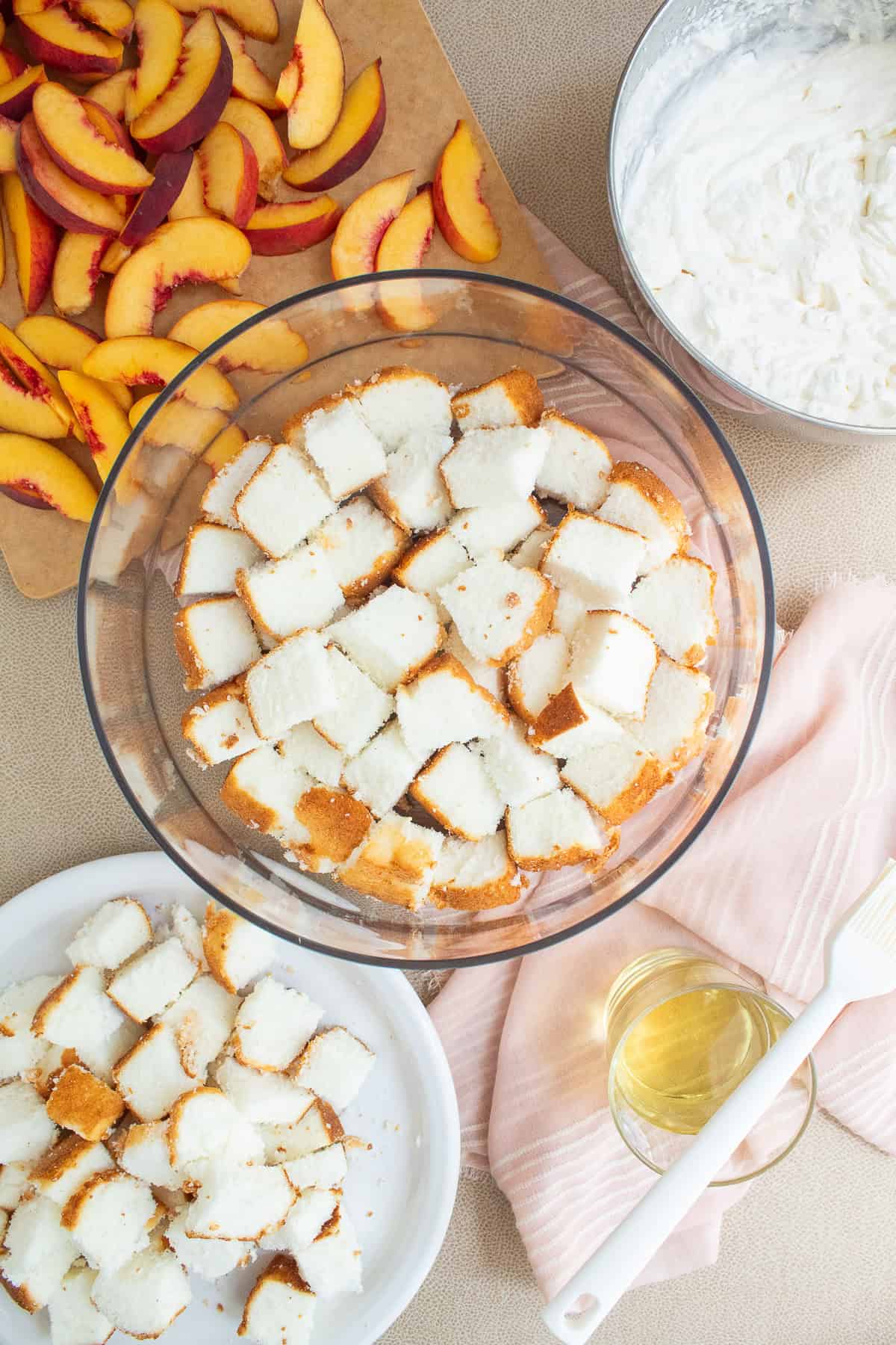 Cubes of angel food cake are arranged in the bottom of a trifle bowl.