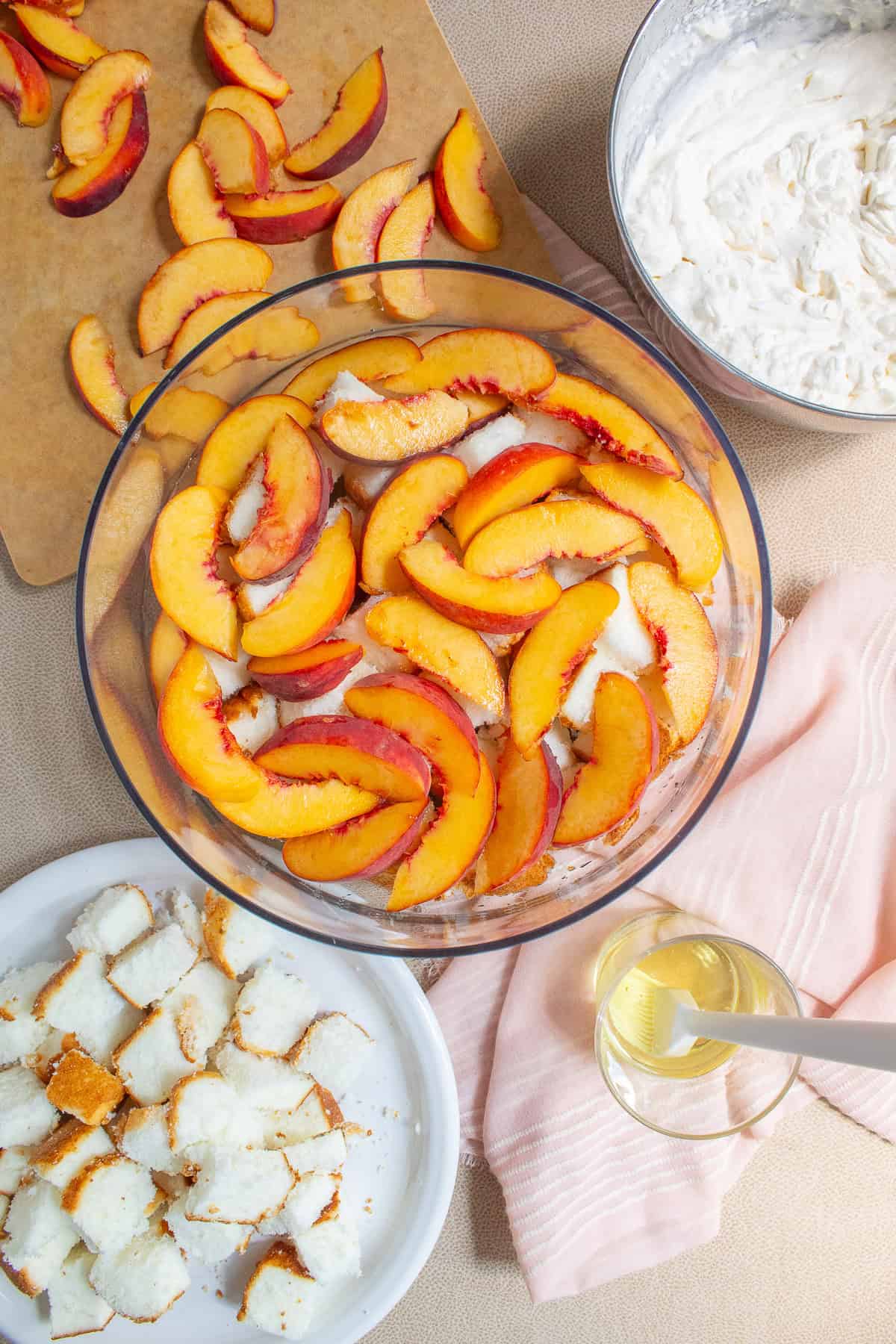 A layer of sliced peaches is placed over the cake and syrup.