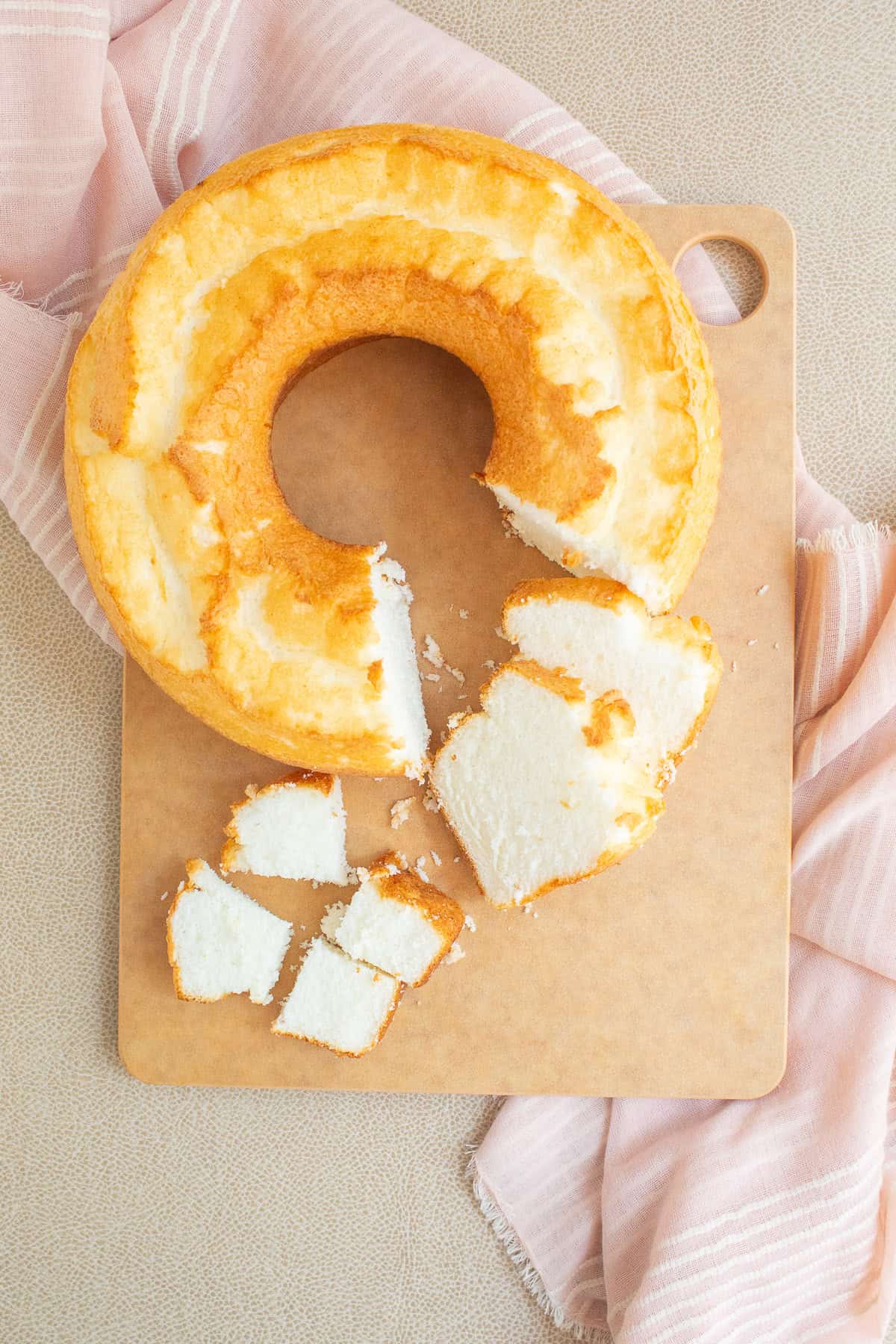 A prepared angel food cake is cut into slices and cubes.