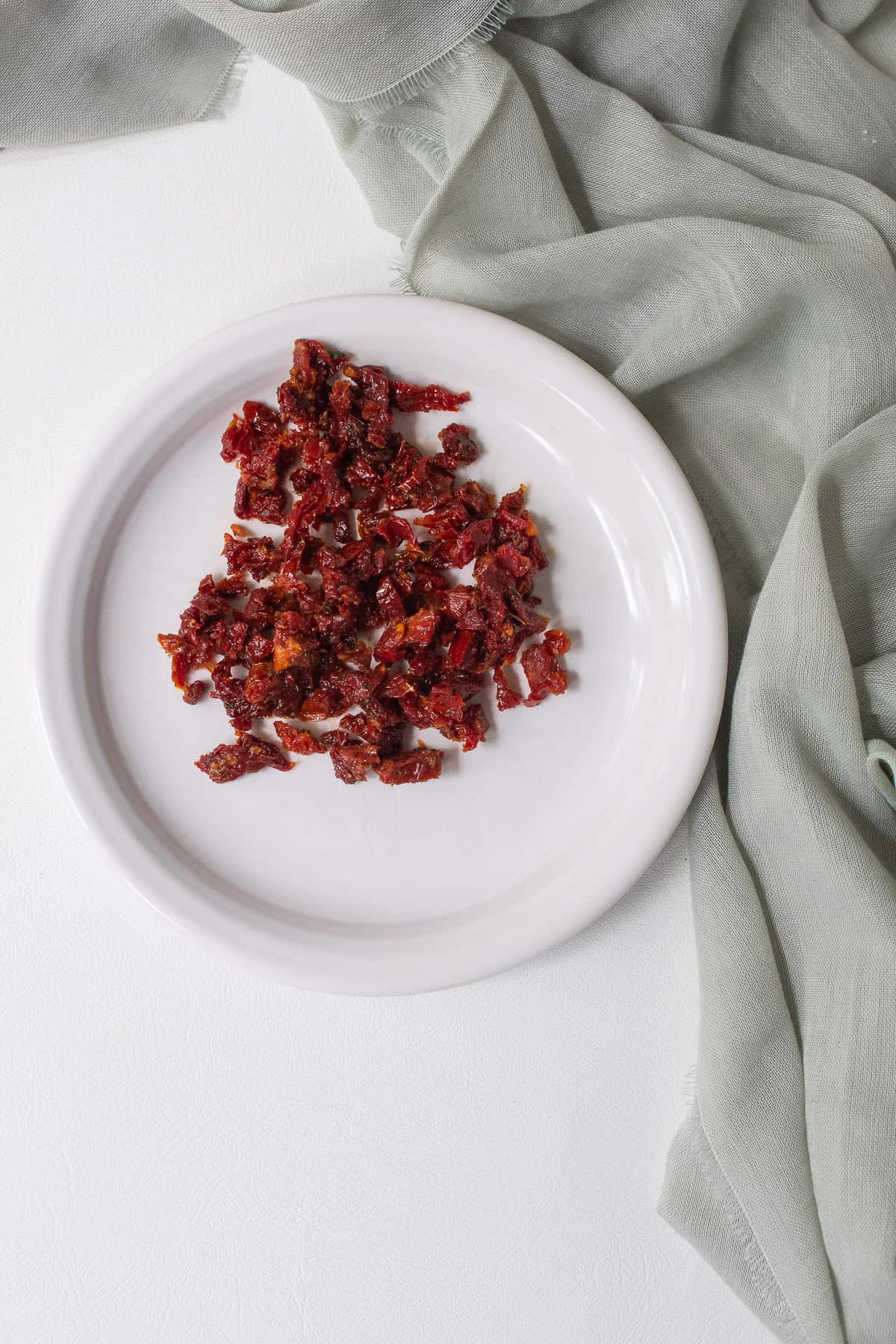 Some sun dried tomatoes are set aside and cut into bite-sized pieces.