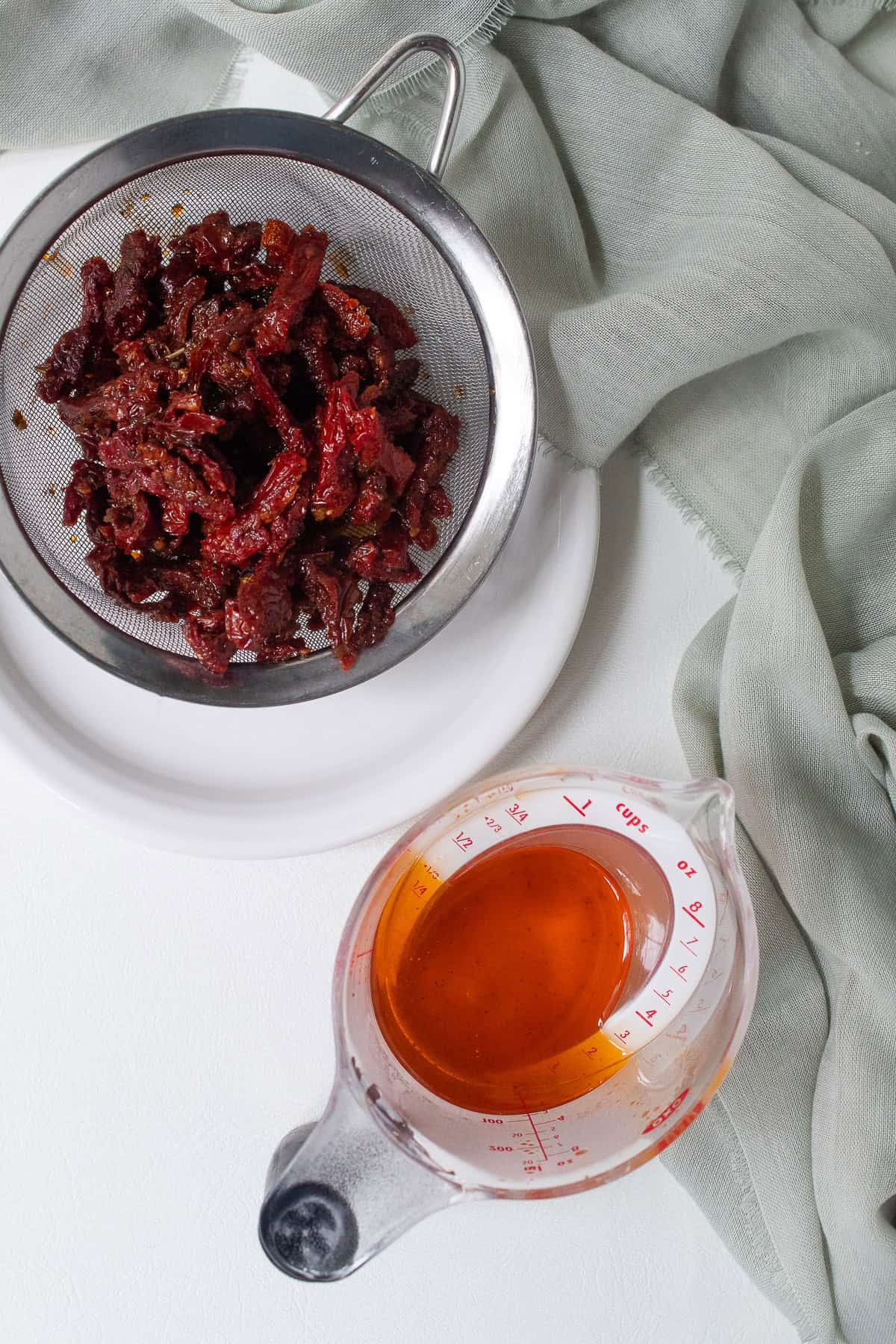 Sun dried tomatoes packed in oil are drained to separate the tomatoes from the dark orange il.