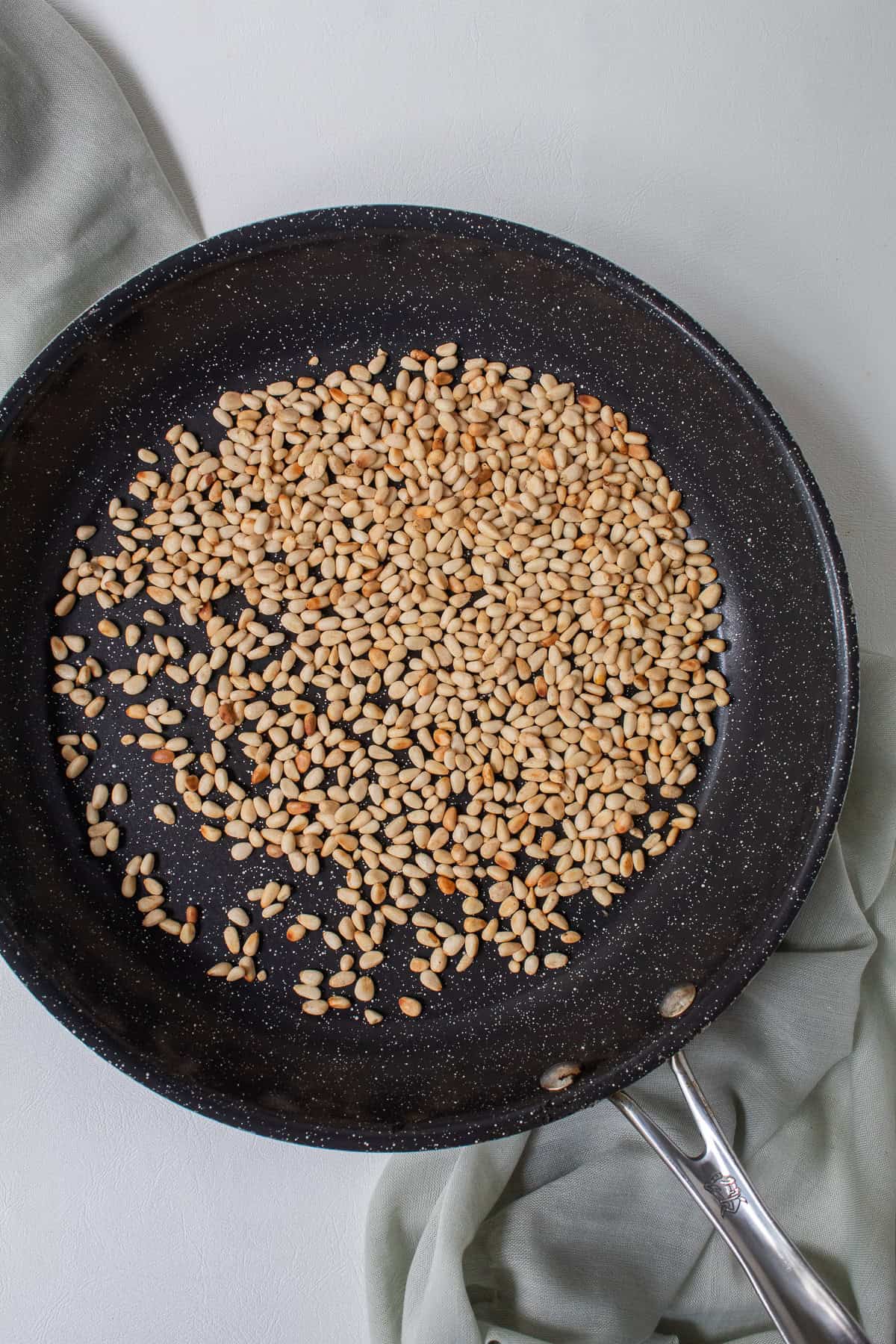 Pine nuts turn from pale yellow to a light golden brown in a skillet.