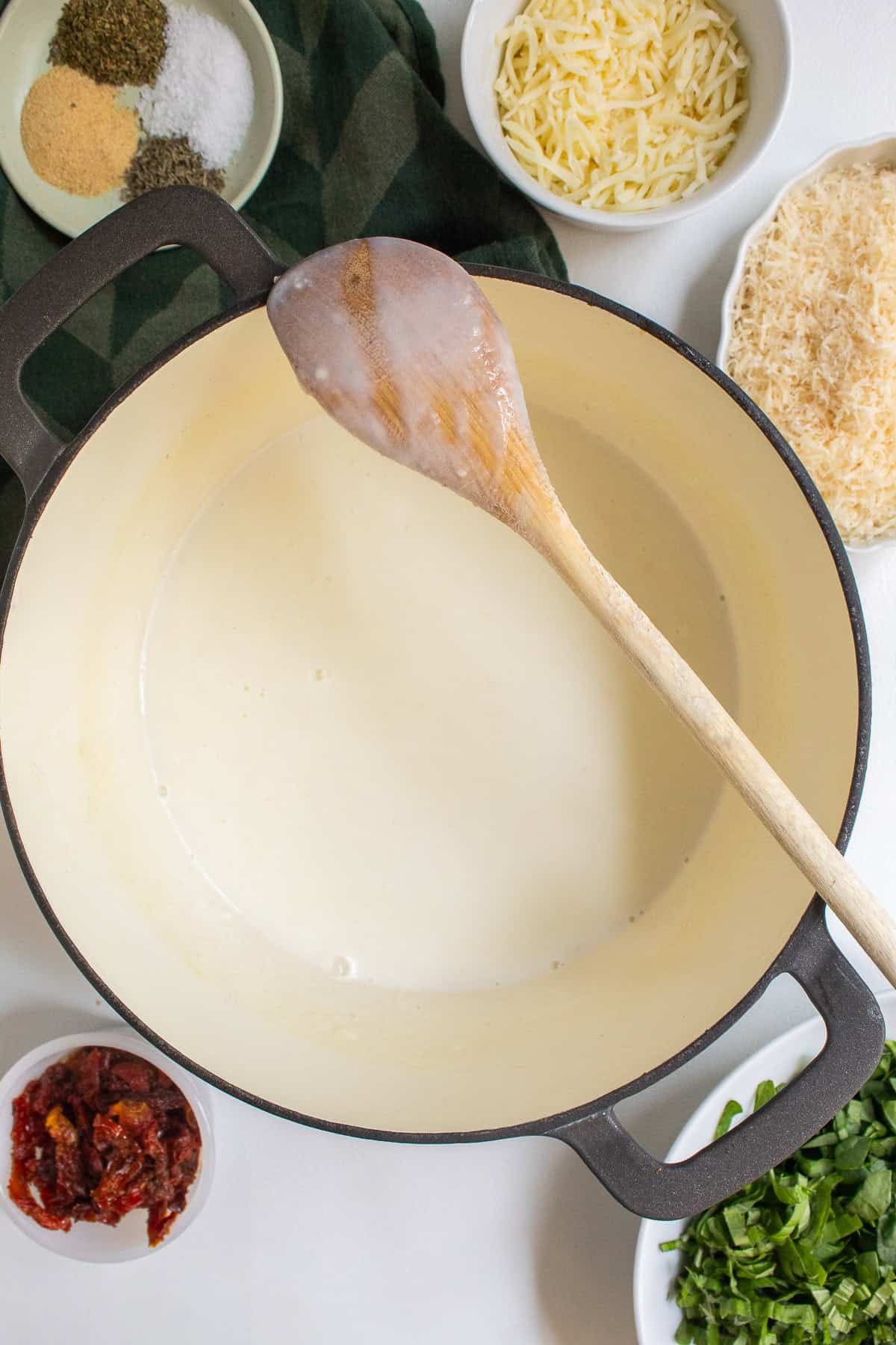 The light bechamel is a pale cream color and has a thin texture as seen on the back of a wooden spoon.