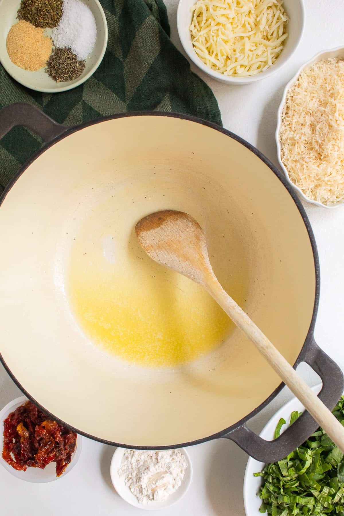 Butter is melted in the bottom of a large Dutch oven and other sauce ingredients are placed around the pot.