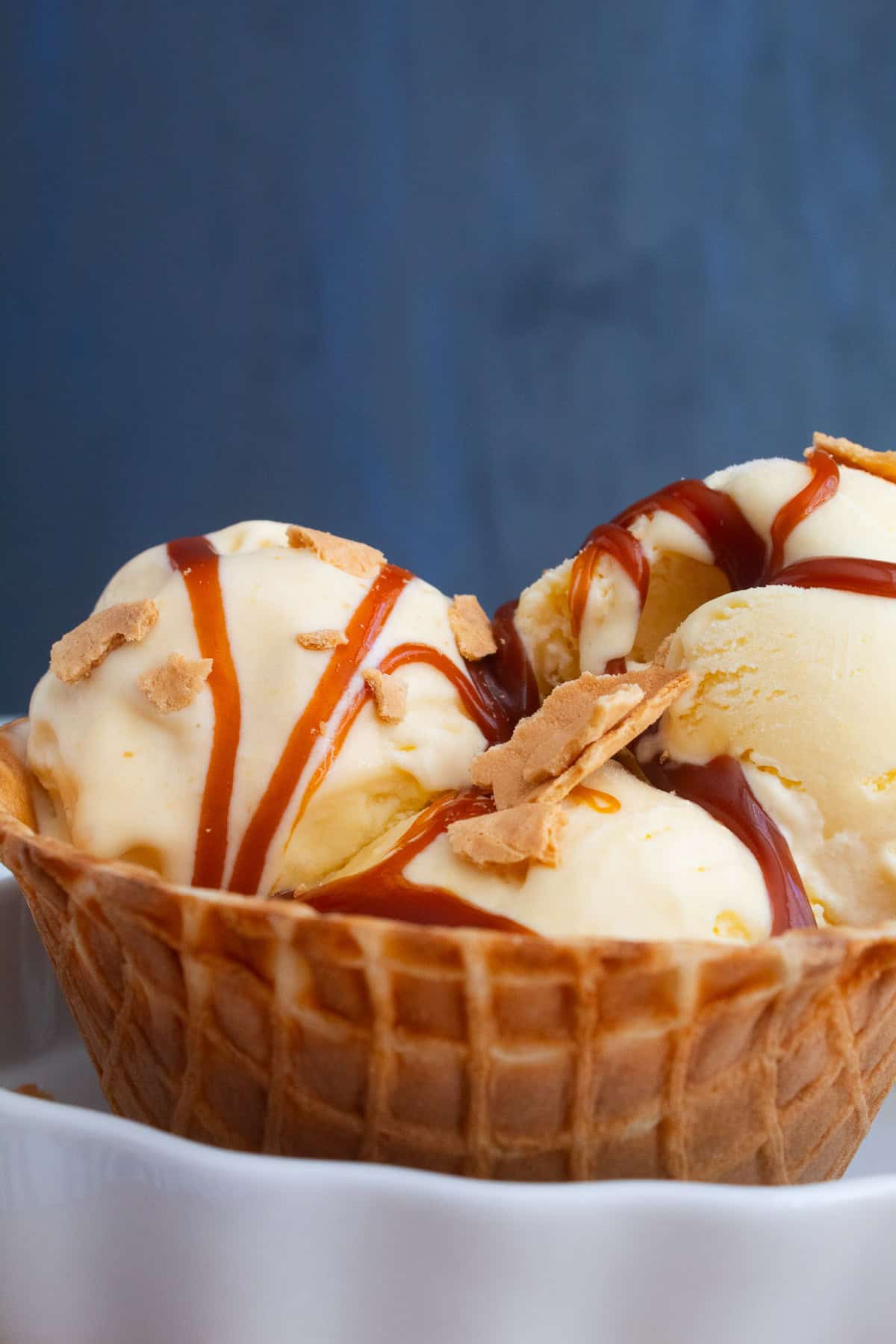 Sweet corn ice cream is served in a waffle cone bowl and drizzled with caramel sauce.