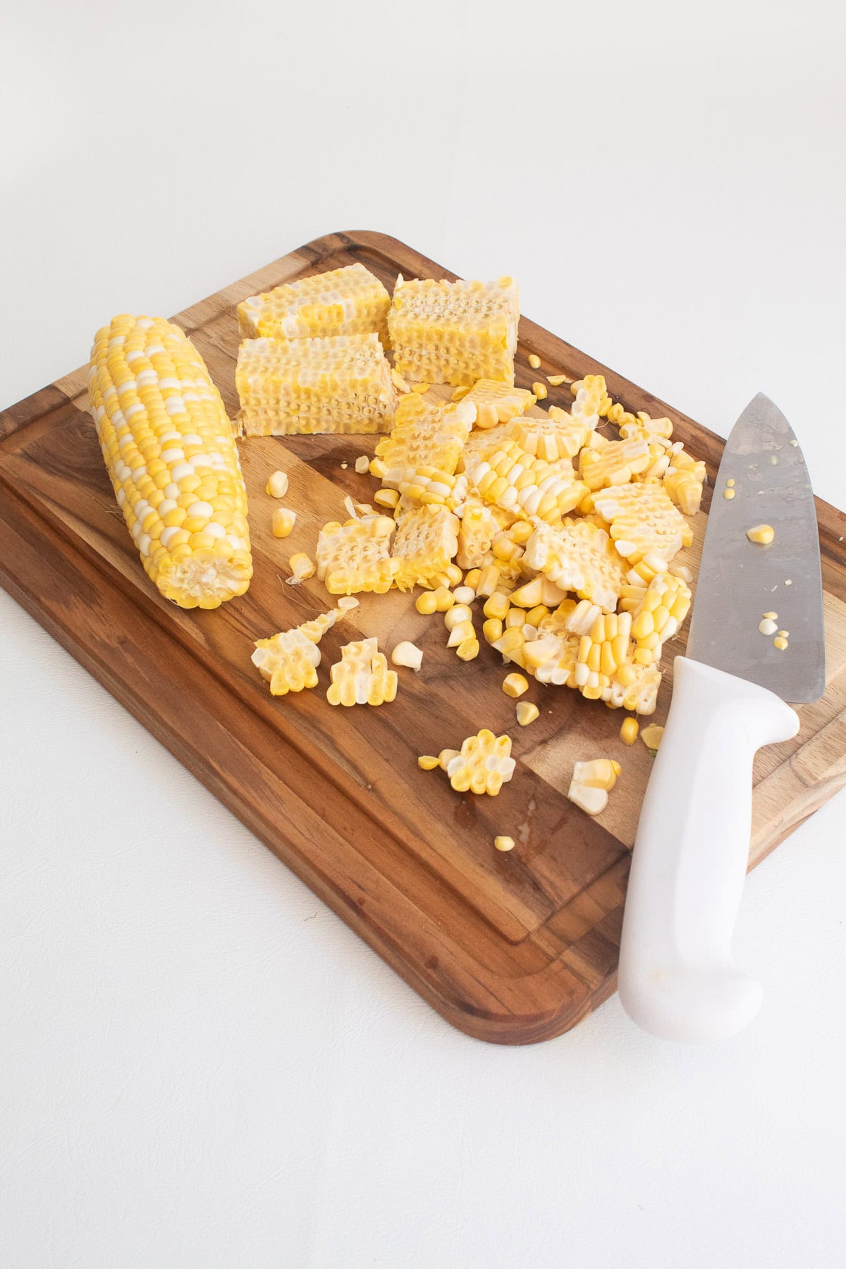 Corn kernels are cut from a cob of fresh corn.