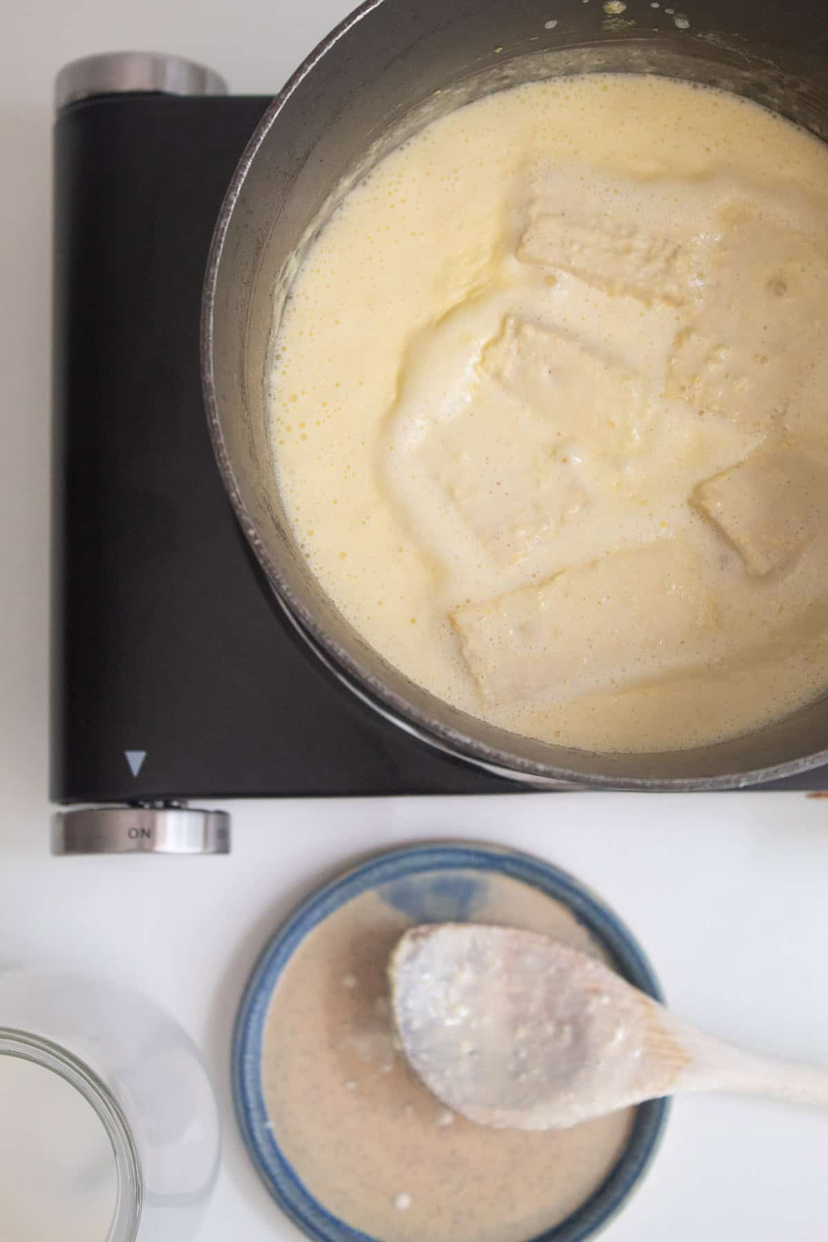 Corn cobs and kernels are in a saucepan with heavy cream.