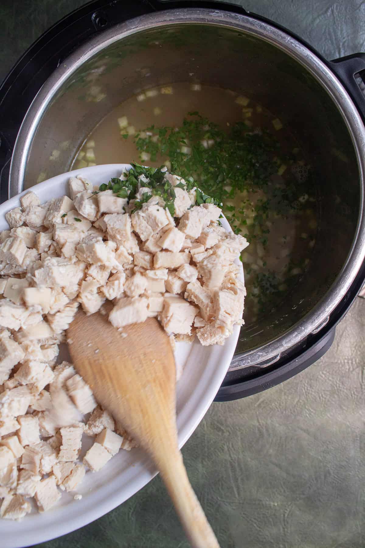 The cooked chicken and chopped parsley are added to the soup.