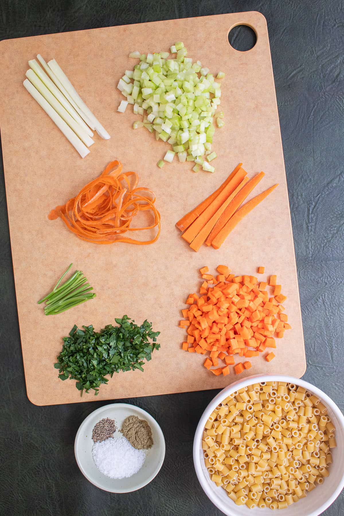 Celery and carrots are cut into strips and then a fine dice while parsley leaves are stripped from the stems and diced.