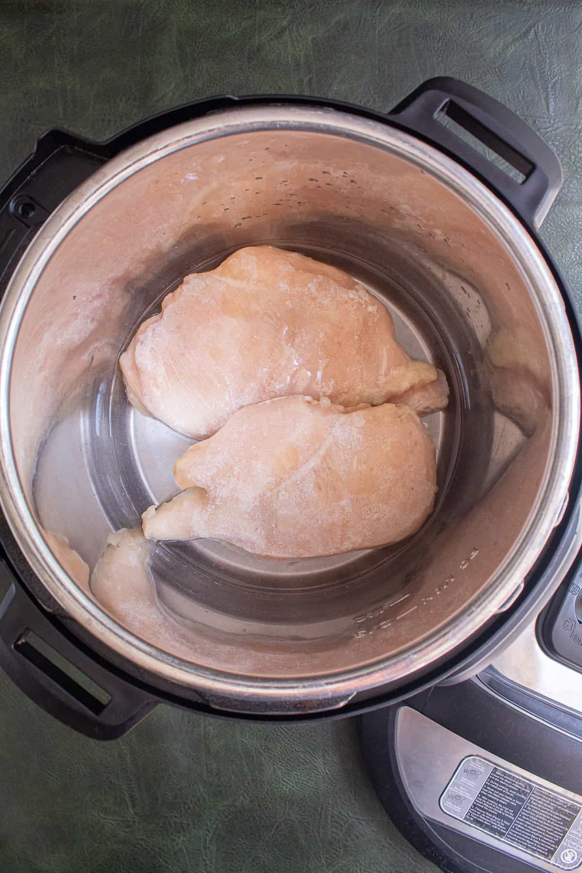 Frozen chicken breasts are added directly to the pressure cooker insert.