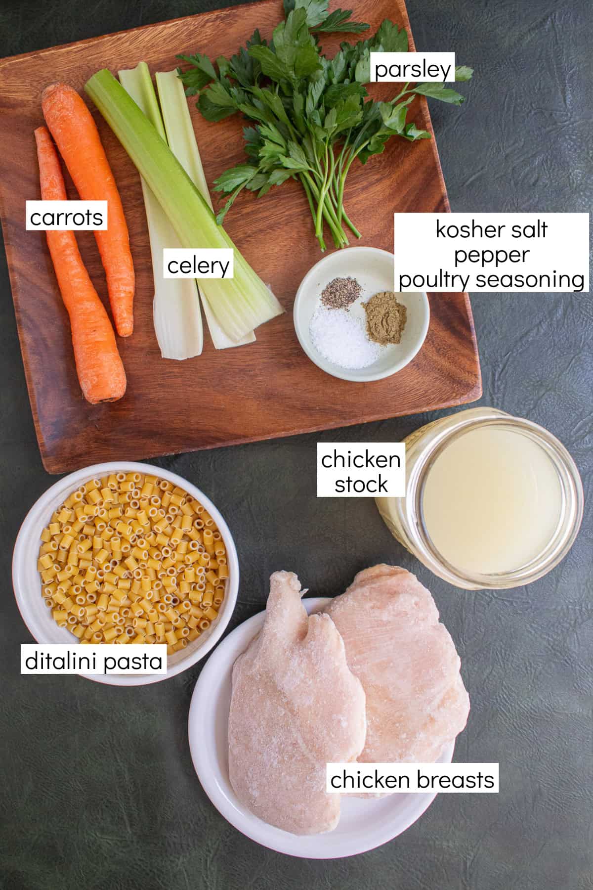 Ingredients for the recipe are displayed and labeled with white text boxes including the words carrots, celery, parsley, kosher salt, pepper, poultry seasoning, chicken stock, ditalini pasta, and chicken breasts.