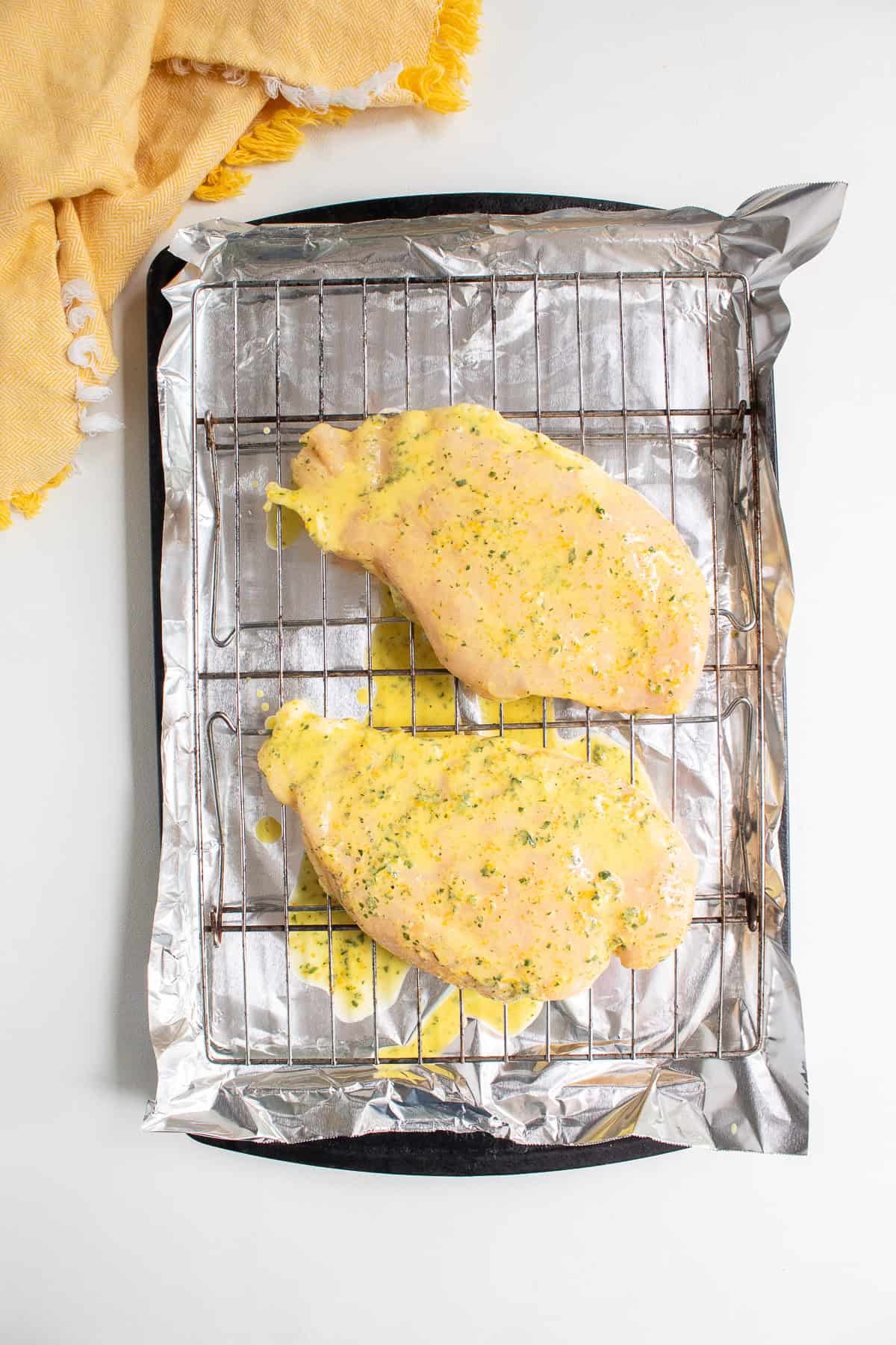 The marinated chicken breasts are laid out on top of the wire rack.