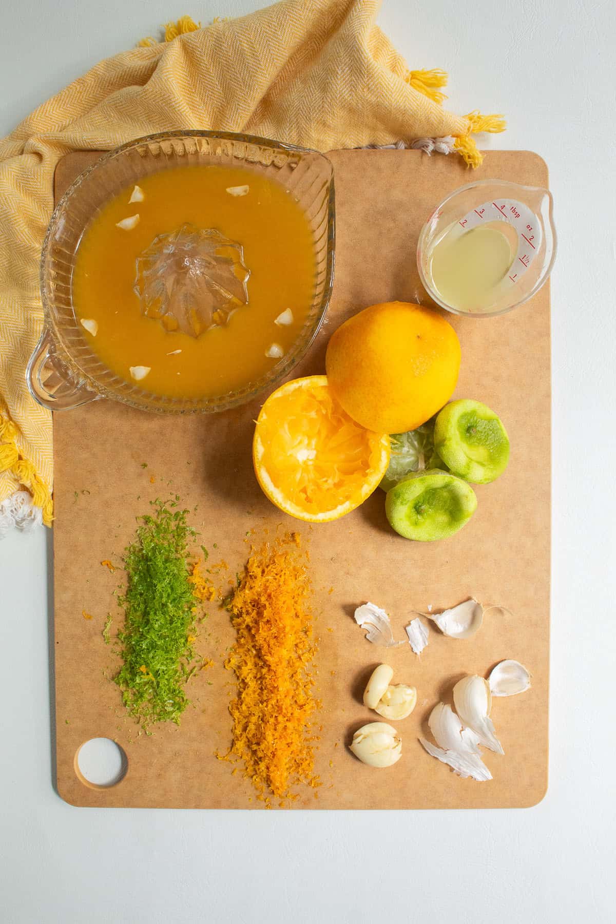 Oranges and limes are zested and juiced while garlic is peeled and crushed.