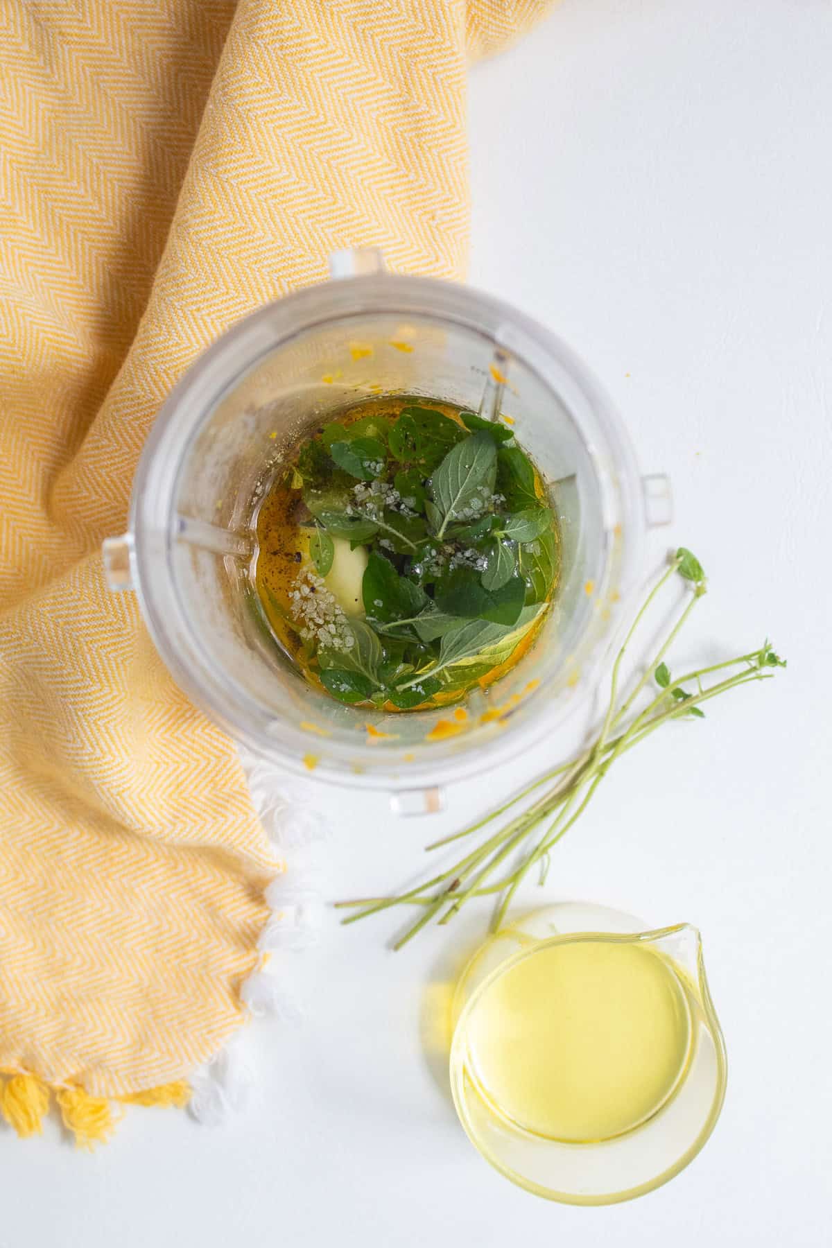 Oregano, garlic, orange juice and zest, salt, oil, and pepper are added to a small blender cup.