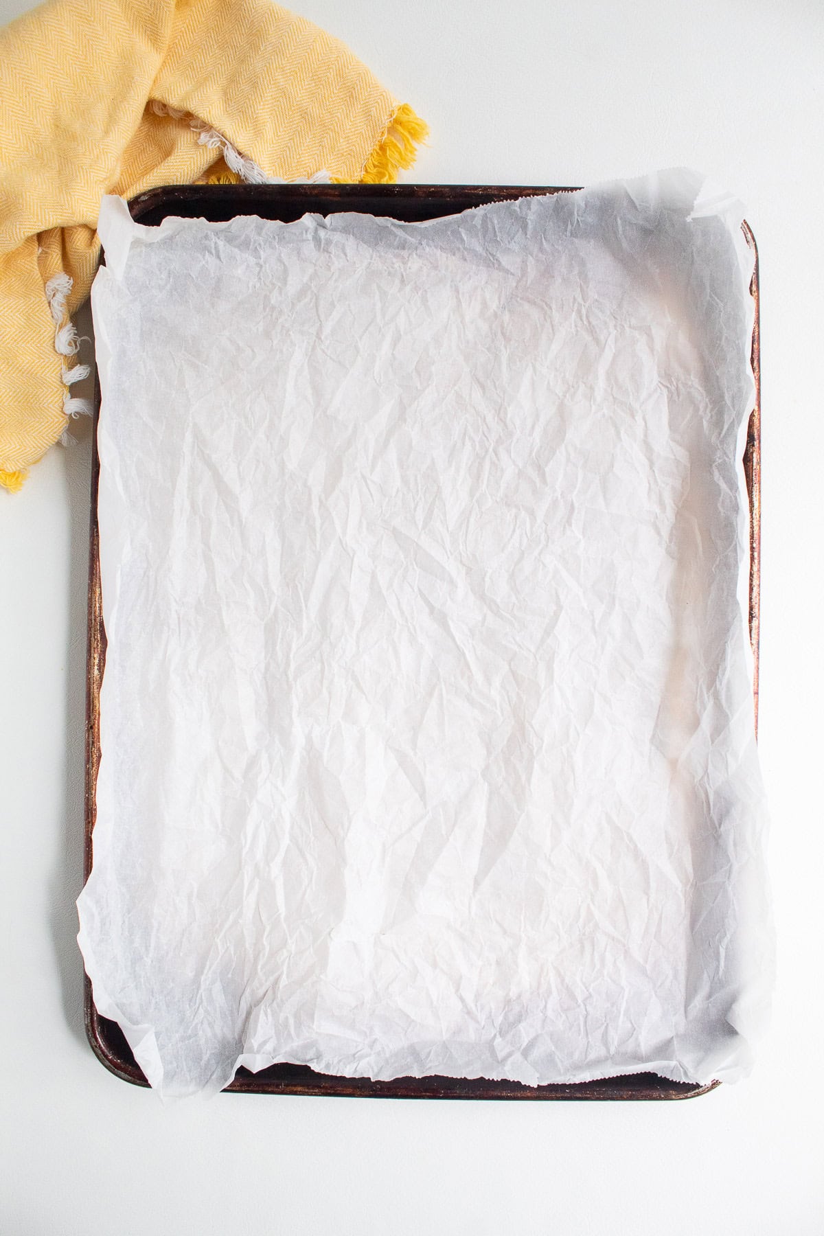 A sheet pan is lined with crinkly parchment paper.