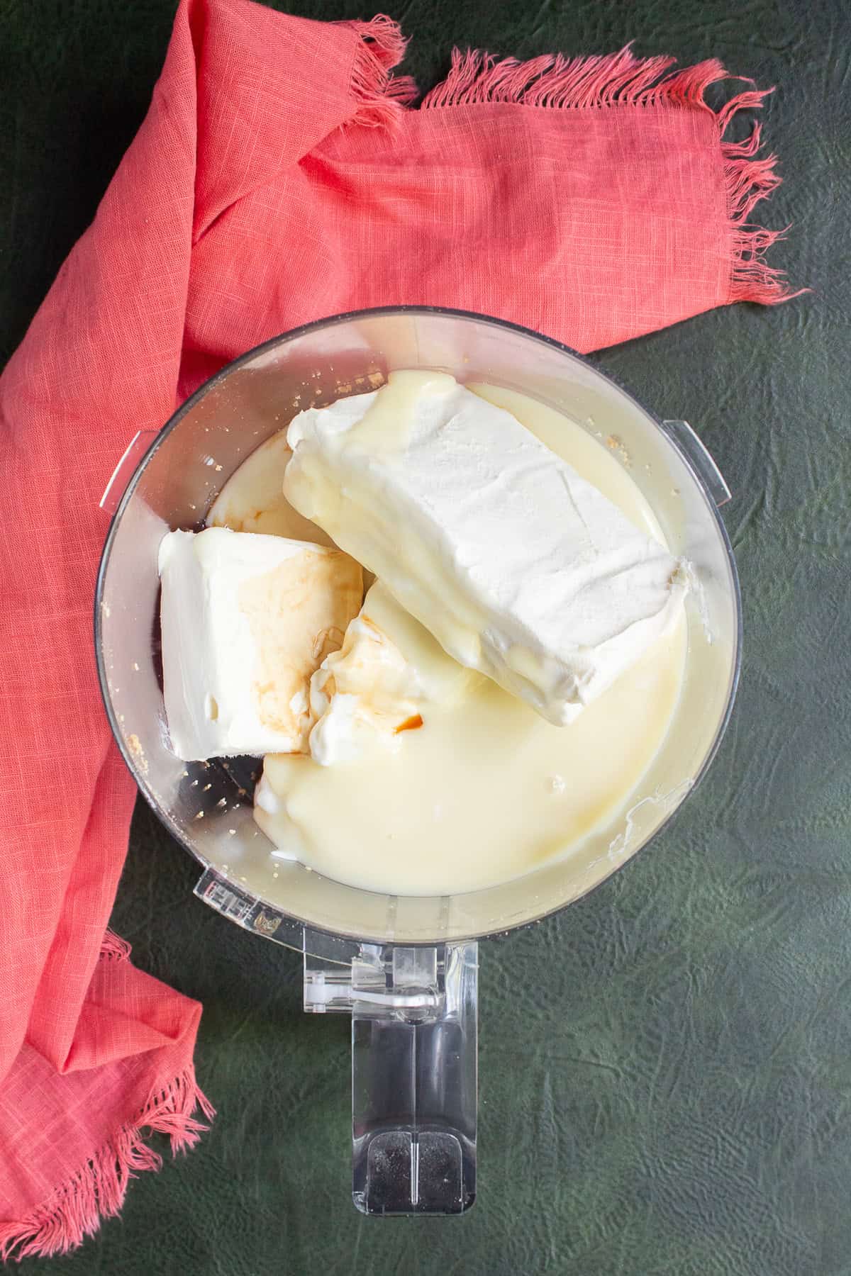 Cream cheese, sweetened condensed milk, vanilla, and Greek yogurt are added to the food processor.