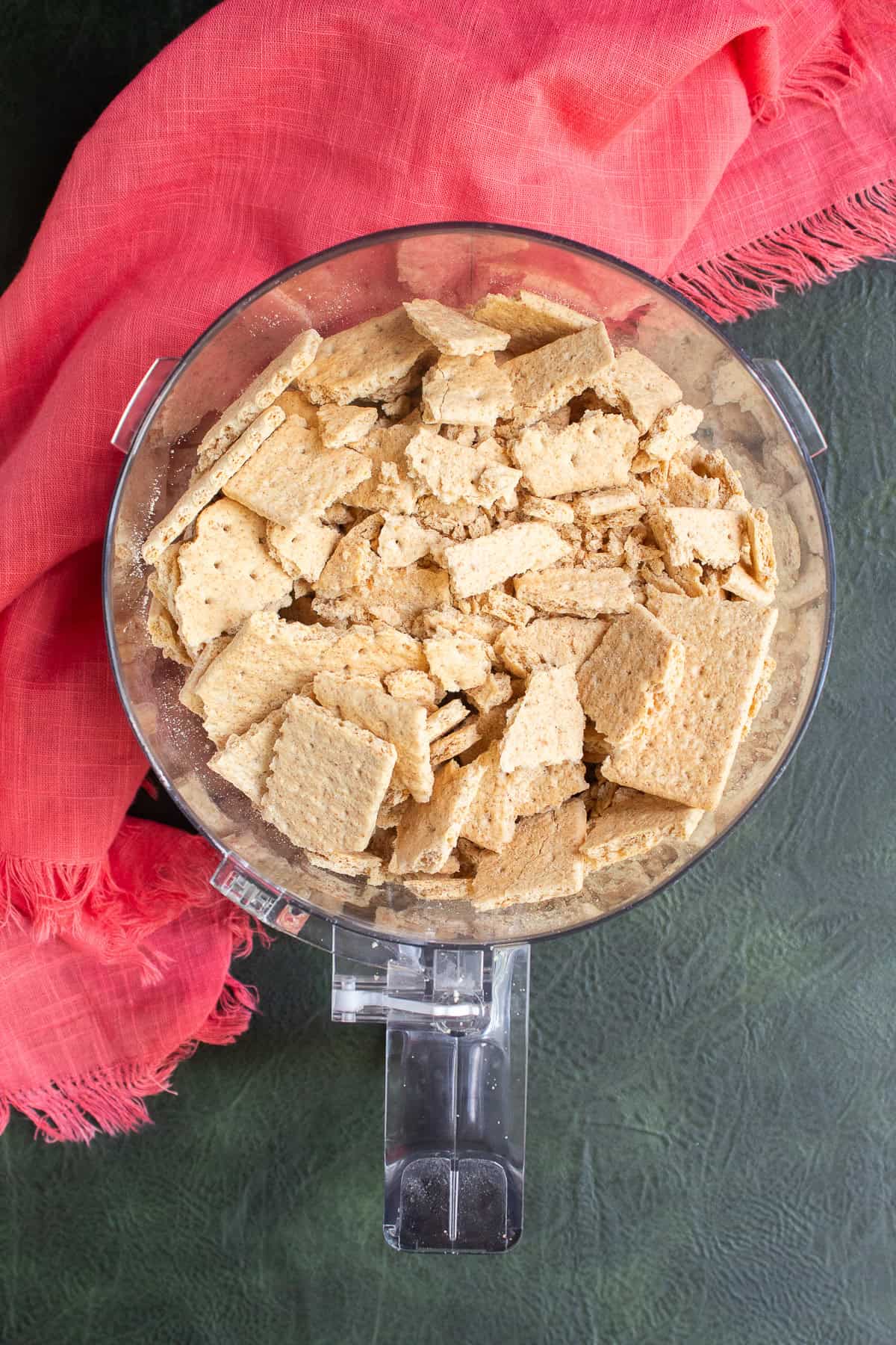 Graham crackers are crushed and then added to a food processor.