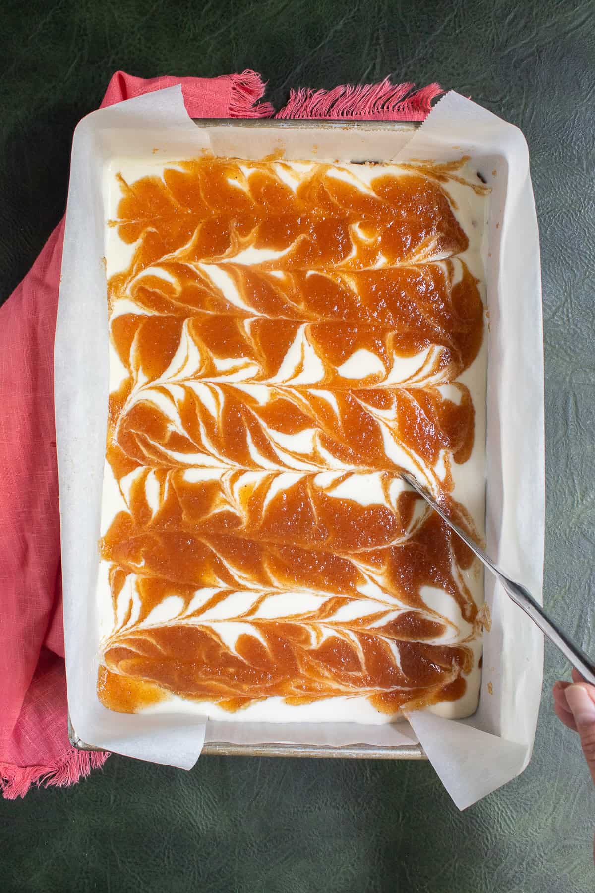 A knife is used to make swirls with the applesauce and cheesecake fillings.