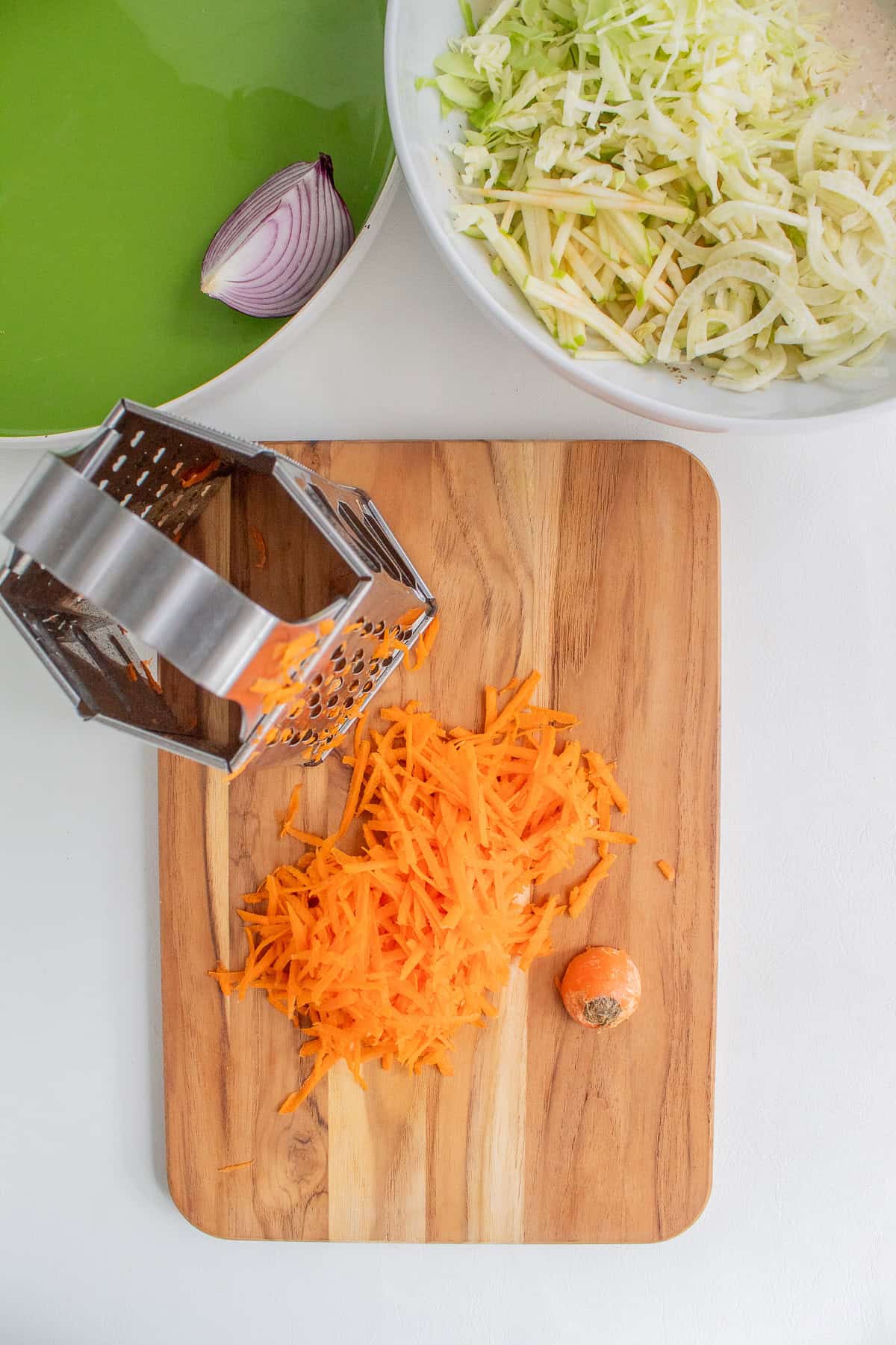 A carrot is shredded using the large holes of a box grater.