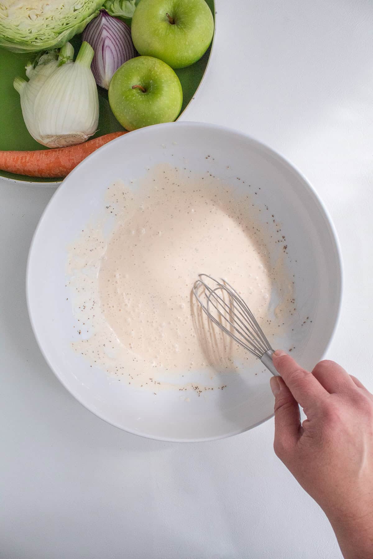 The slaw dressing is whisked together in a mixing bowl.