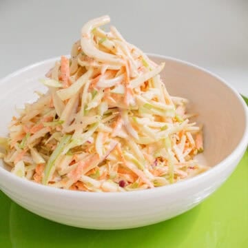 The slaw contains visible pieces of green apples, red onions, cabbage, carrots, and fennel in thin shreds.