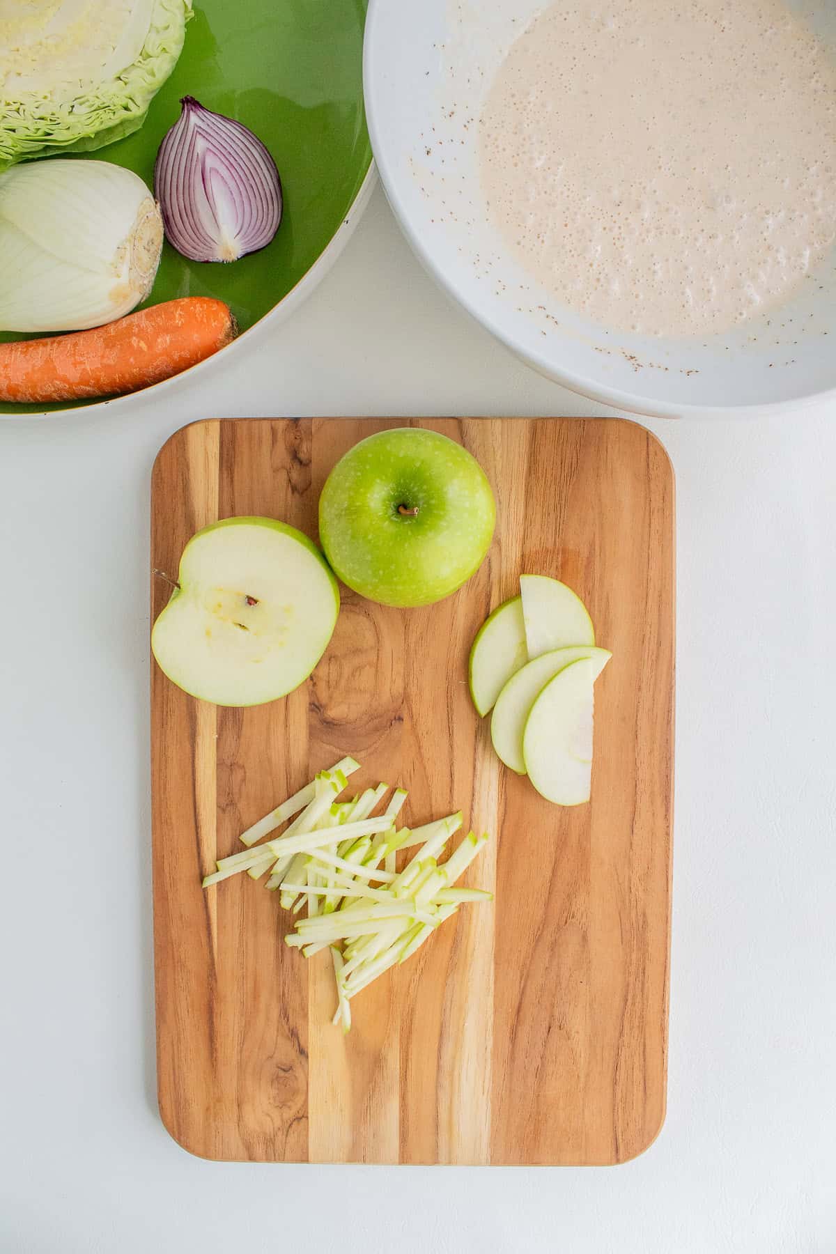 A Granny Smith apple is sliced into thin julienne strips.