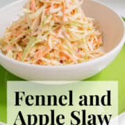 The dressed slaw is piled high in a white serving bowl on a green platter A white text box at the bottom of the image contains the words, "fennel and apple slaw" and "plan. eat. post. repeat."
