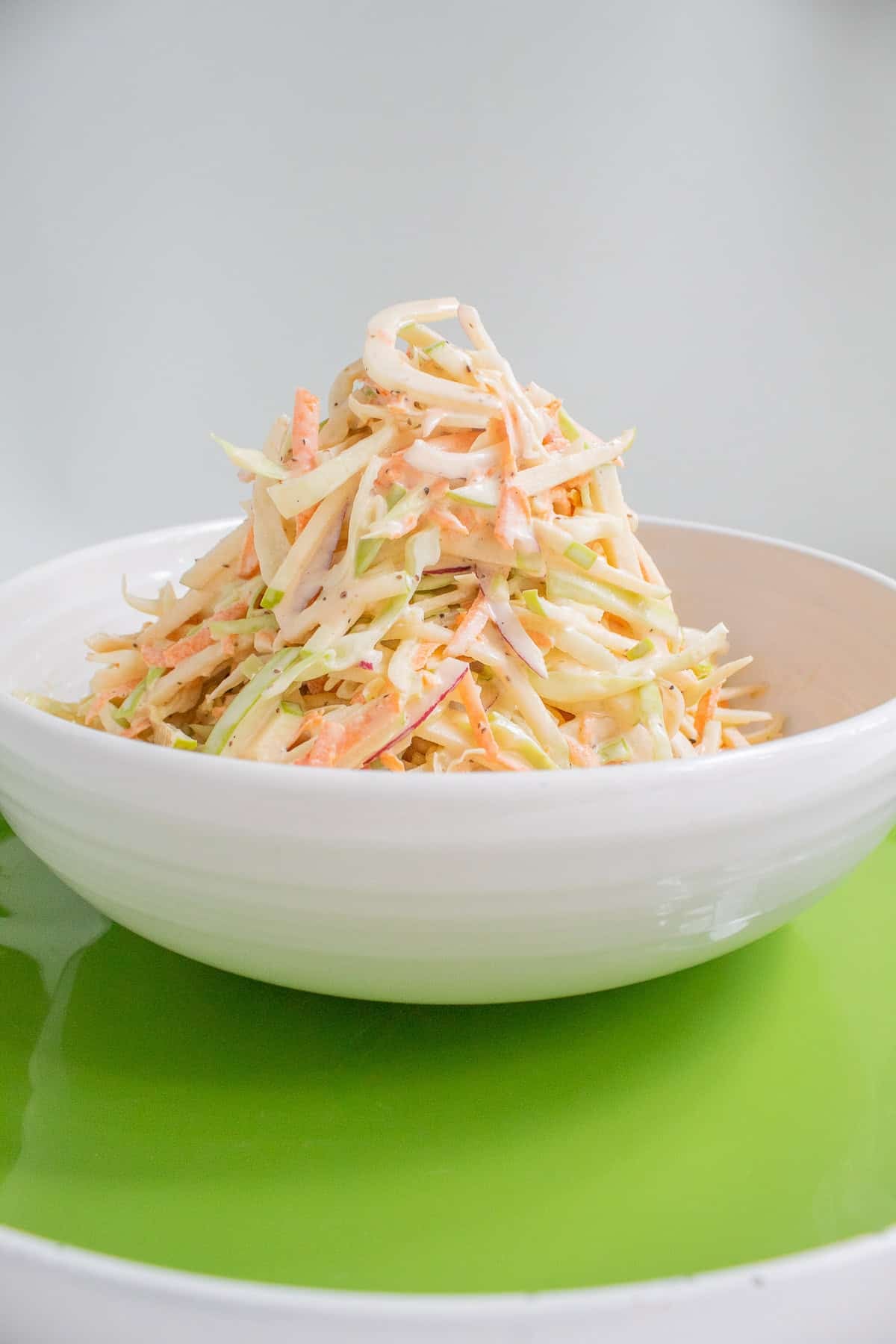 The slaw is piled high in a white serving bowl.