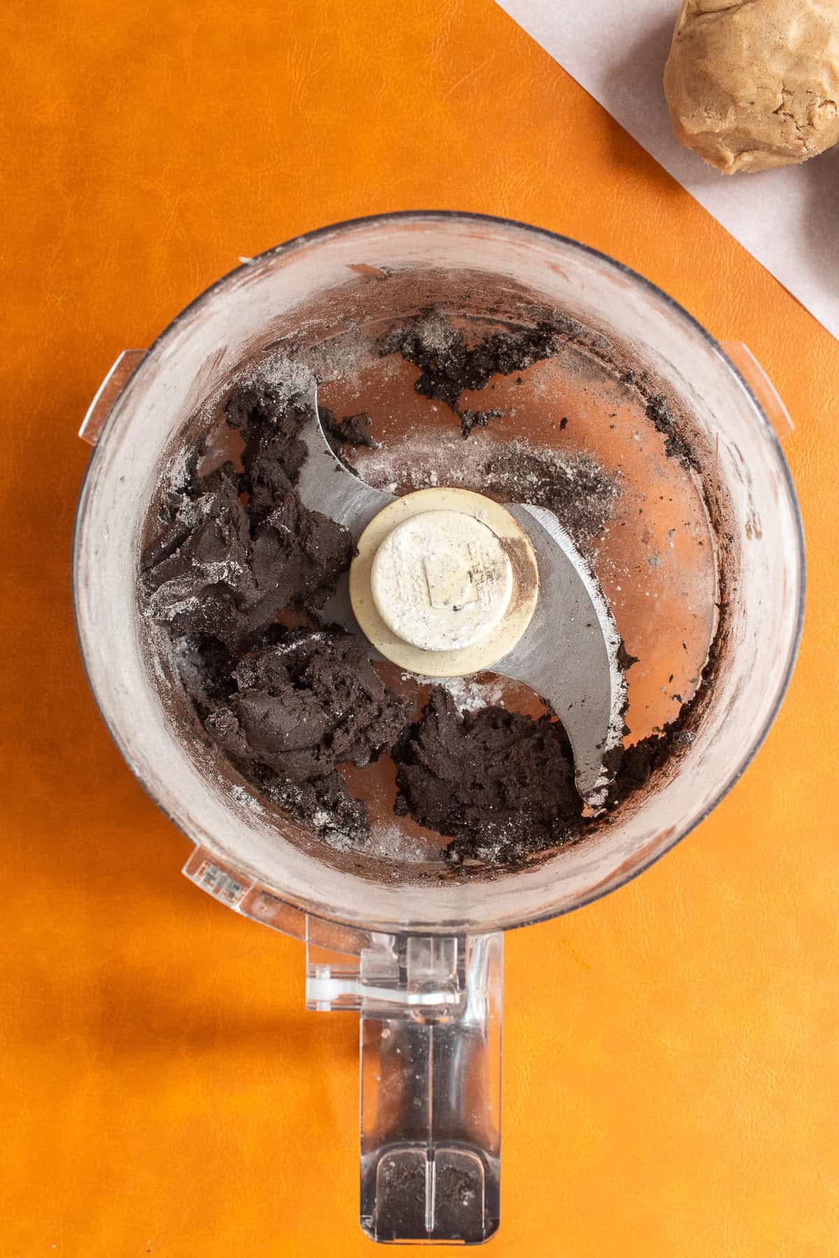 The dark cocoa dough is processed until it forms a ball in the bowl.