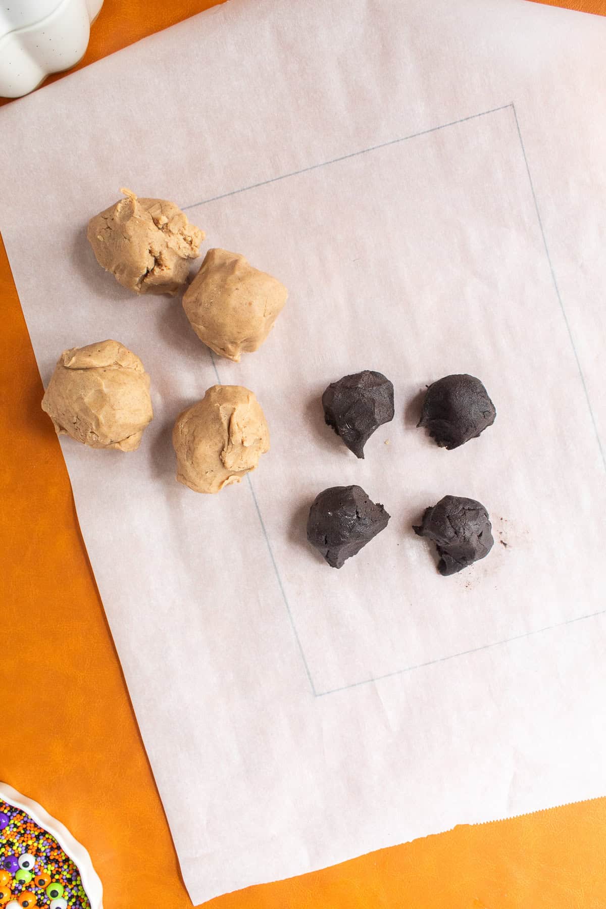 Four balls of spiced shortbread dough are piled next to four balls of chocolate dough.