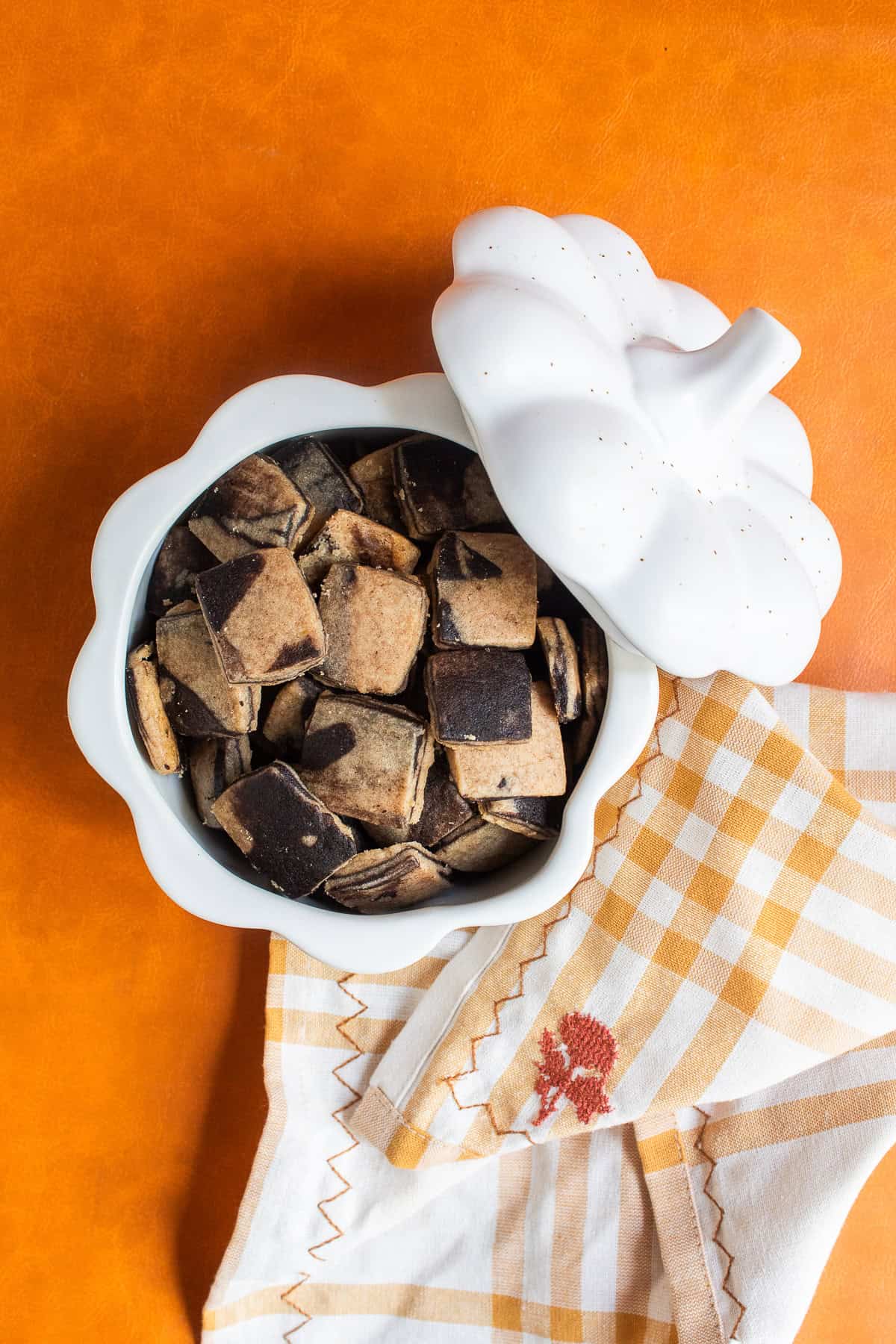 Tiny marbled shortbread cookies are piled in a pumpkin-shaped bowl.