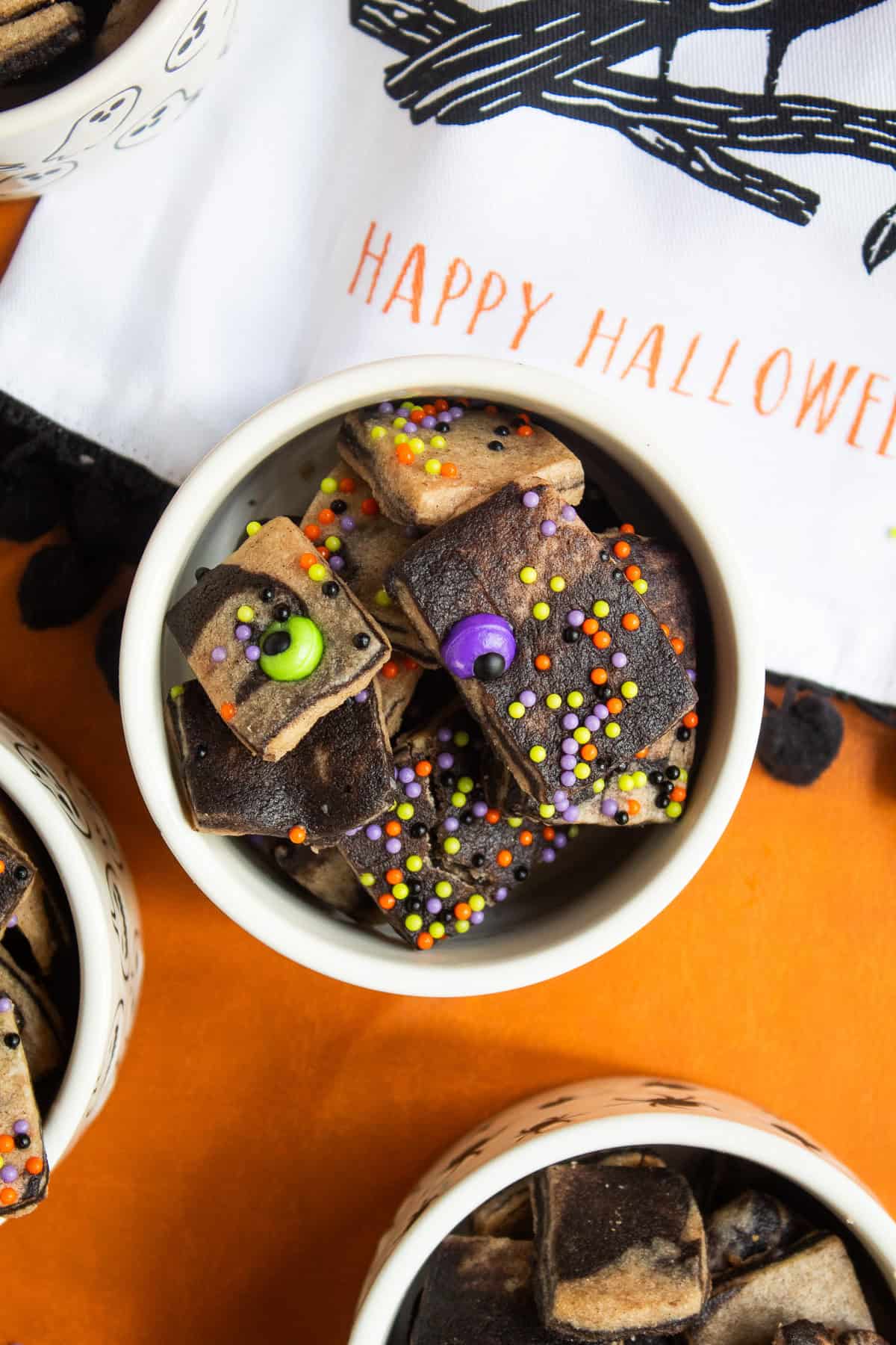 The baked cookies are dotted with orange, green, purple, and black sprinkles.