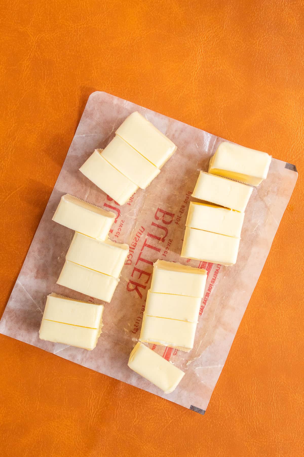 Two sticks of unsalted butter are cut into pieces.