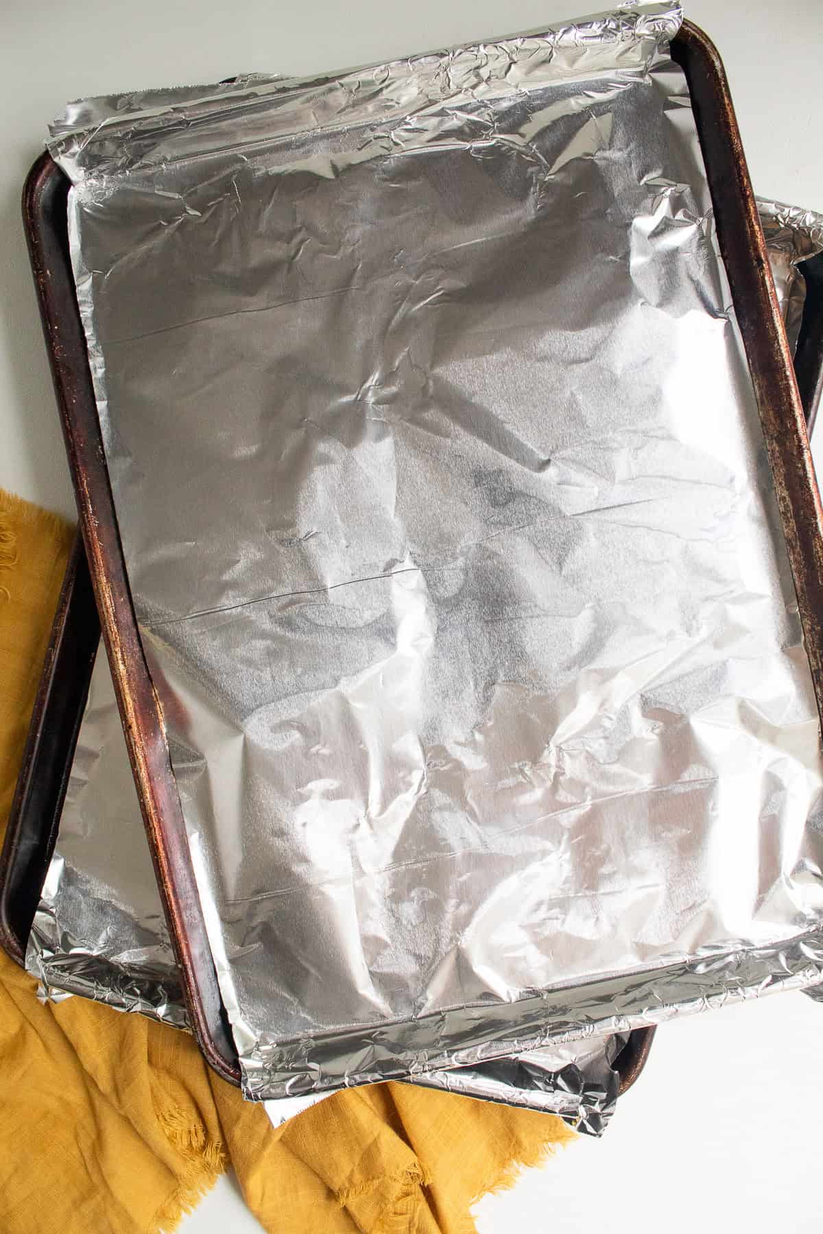 Two half sheet pans are lined with foil.