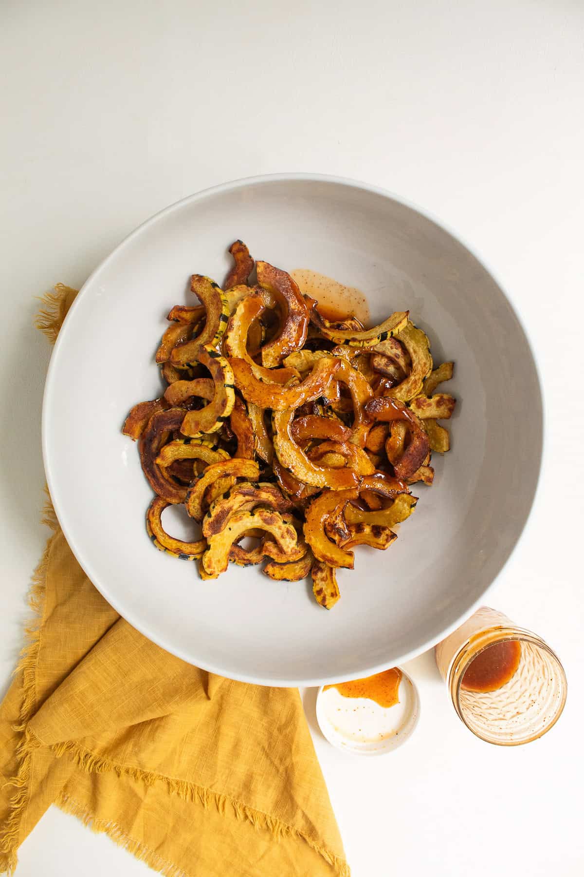 The ancho chile vinaigrette is poured over the warm roasted squash in a large white bowl.