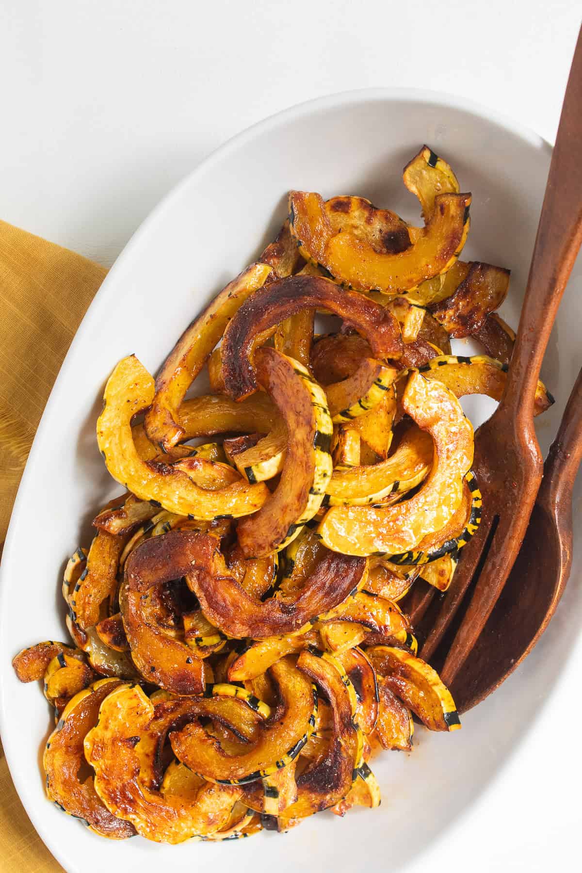 The glazed squash is transferred to an oblong serving bowl.
