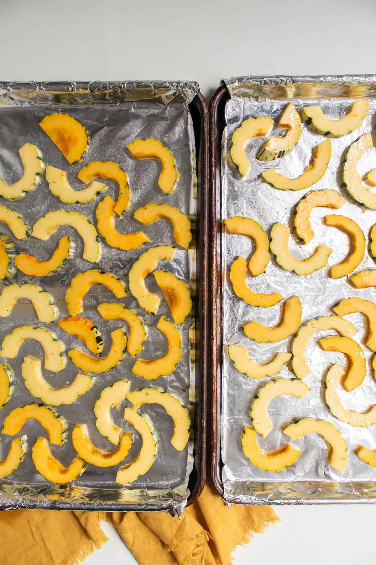 The squash slices are spread out over two baking sheets.