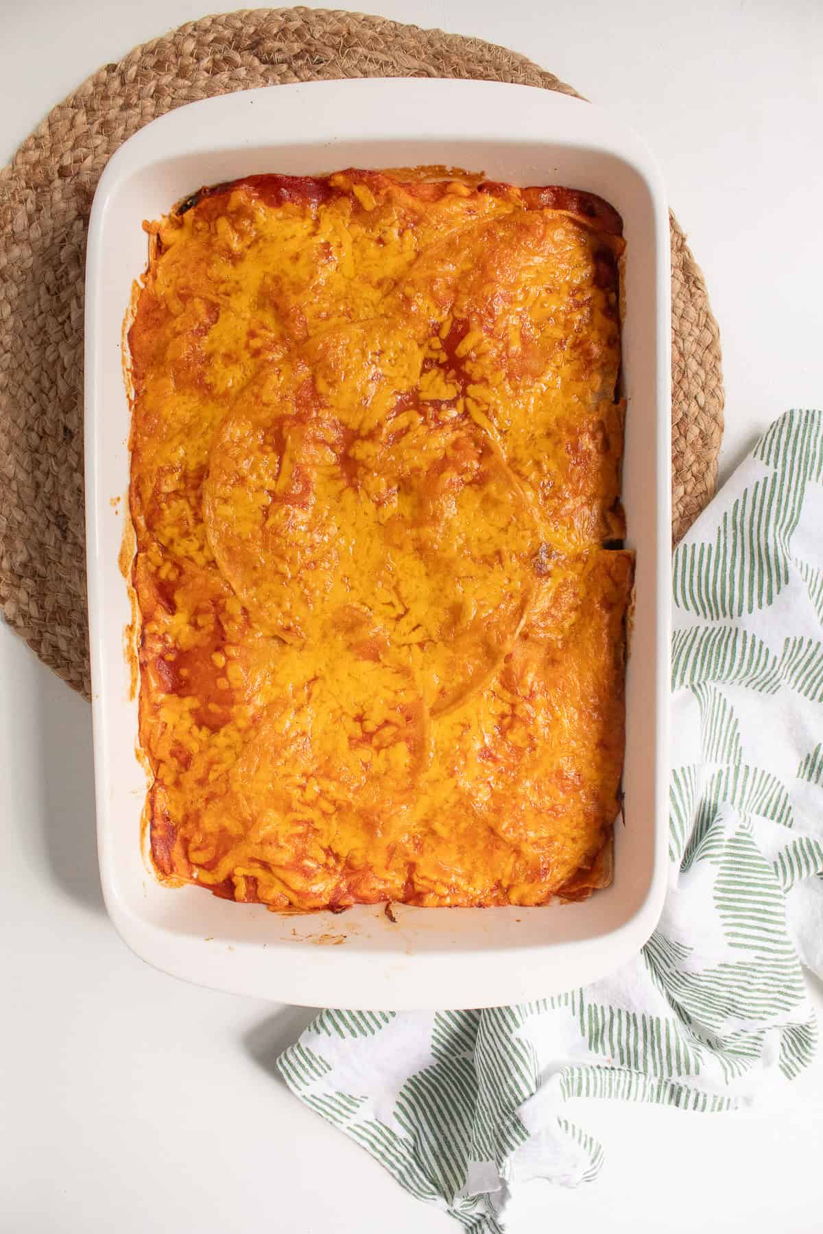 The finished enchiladas are golden on top with bubbling red enchilada sauce at the edges.