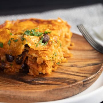 A slice of the enchiladas shows layers of tortillas, black beans, and cheese.