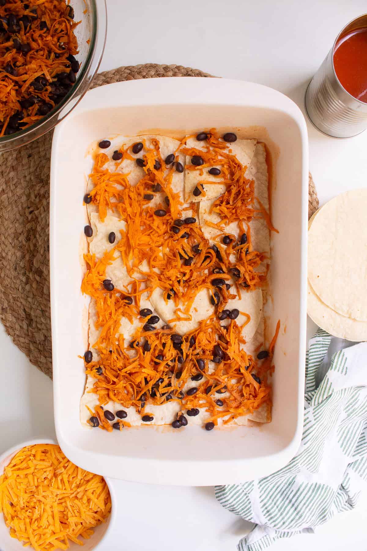 The first layer of the spiced sweet potato and black bean filling is sprinkled over the tortillas.