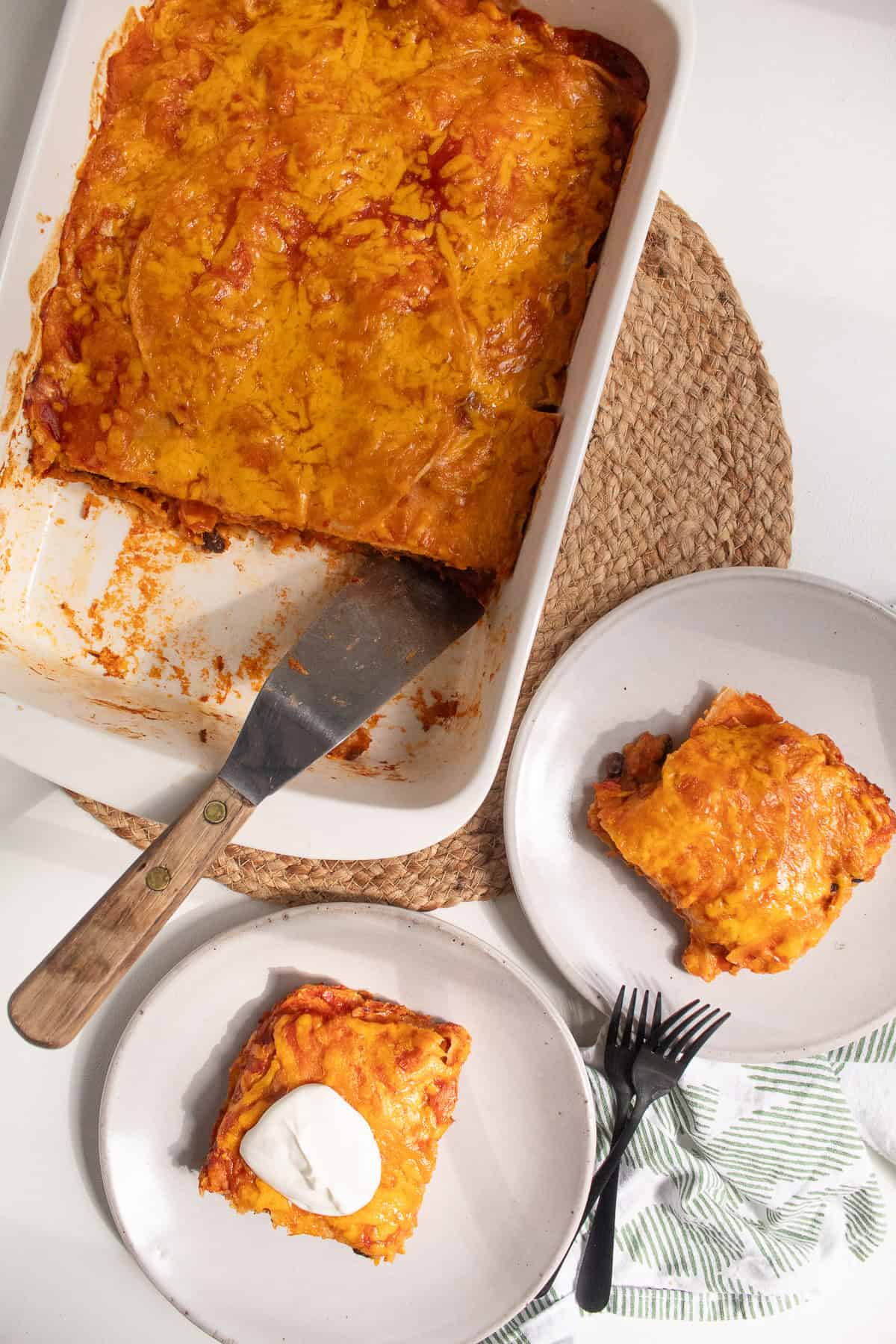 Squares of the enchiladas are served with a wood-handled spatula.