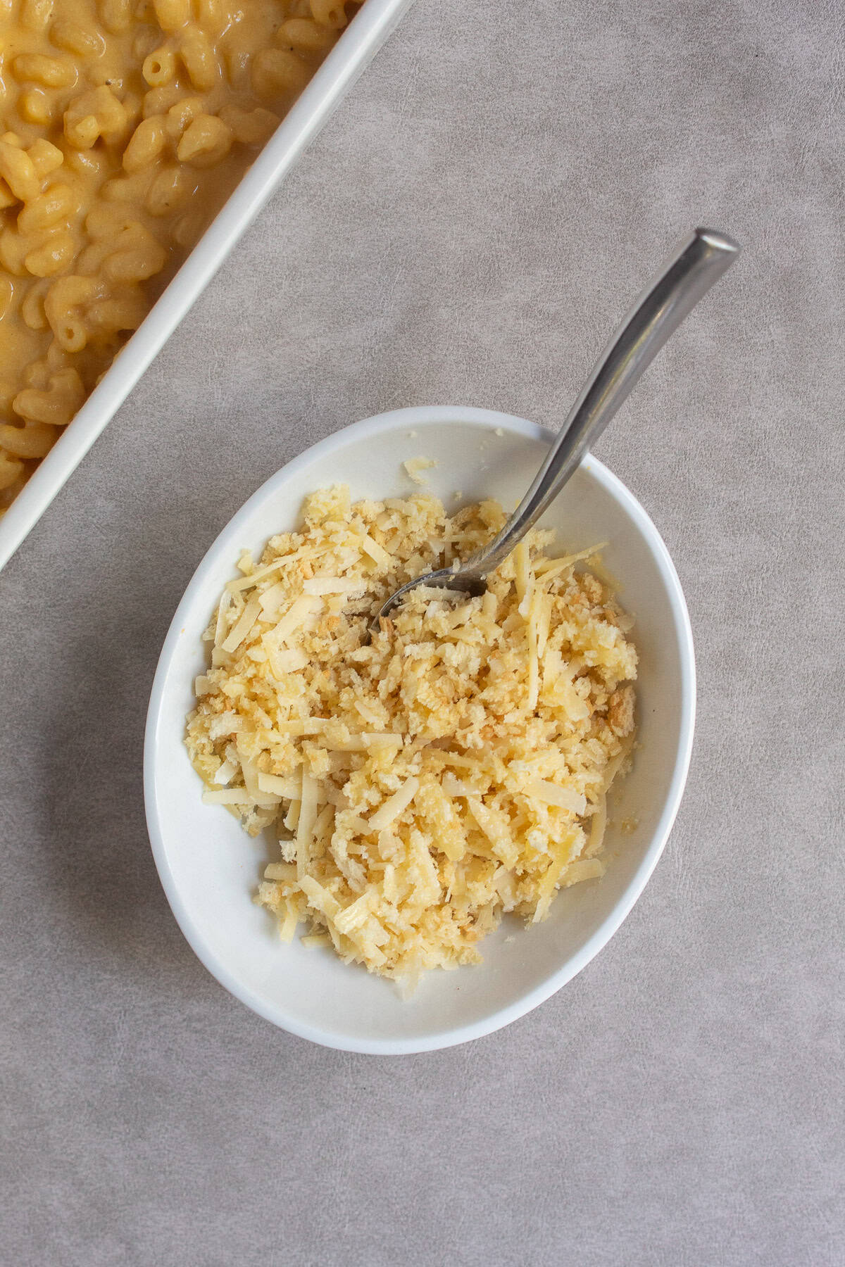 The cheese, bread crumb, and butter mixture is combined in a medium white bowl.